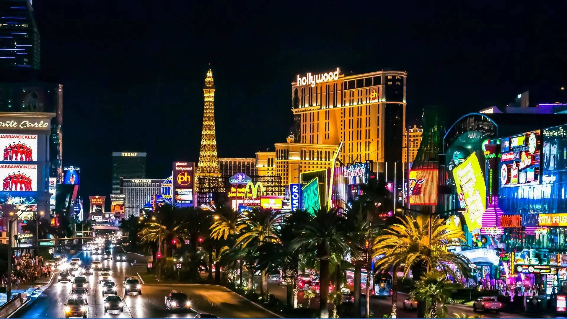 Las Vegas 桌布 壁紙 — 充滿活力的霓虹燈照亮了夜晚繁忙的拉斯維加斯大道，棕櫚樹和標誌性酒店在黑暗的天空下閃耀。