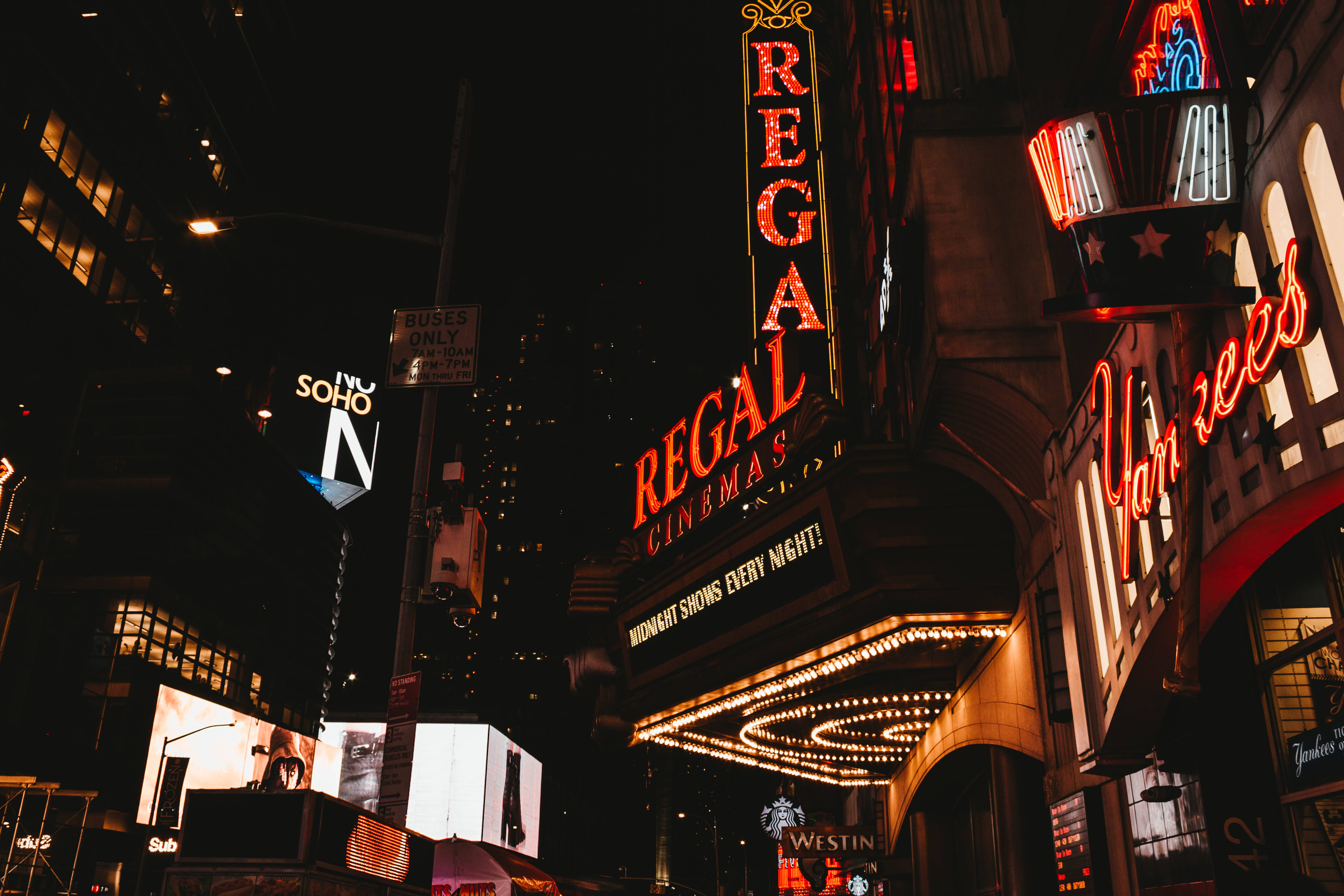 New 桌布 壁紙 — 充滿活力的霓虹燈照亮了夜晚繁忙的紐約市街道，Regal Cinemas 和 Yankees 的標誌閃爍明亮。