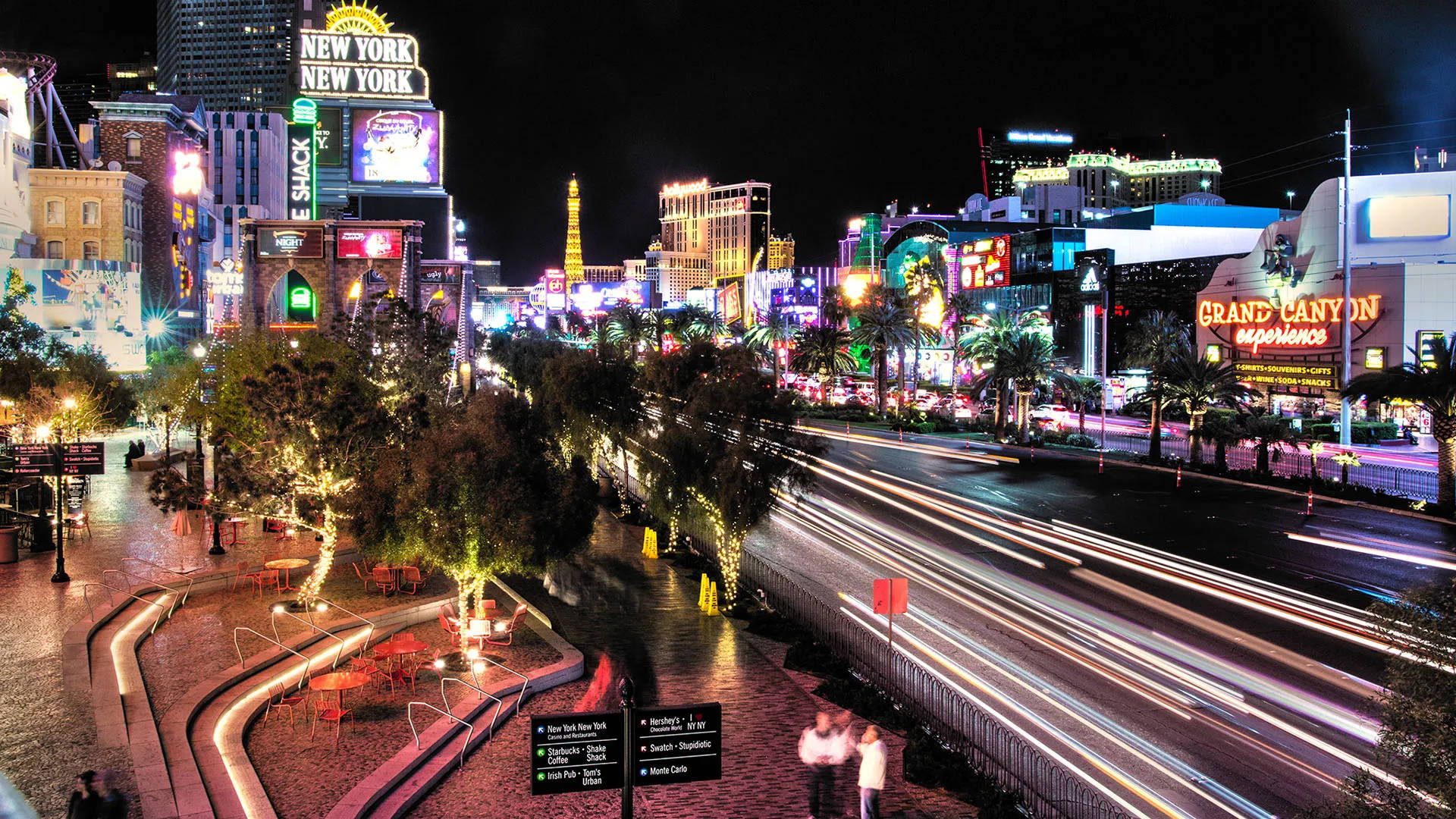 Las Vegas 桌布 壁紙 — 充滿活力的霓虹燈照亮了夜晚繁華的拉斯維加斯大道，車燈流光溢彩，街道兩旁棕櫚樹林立。