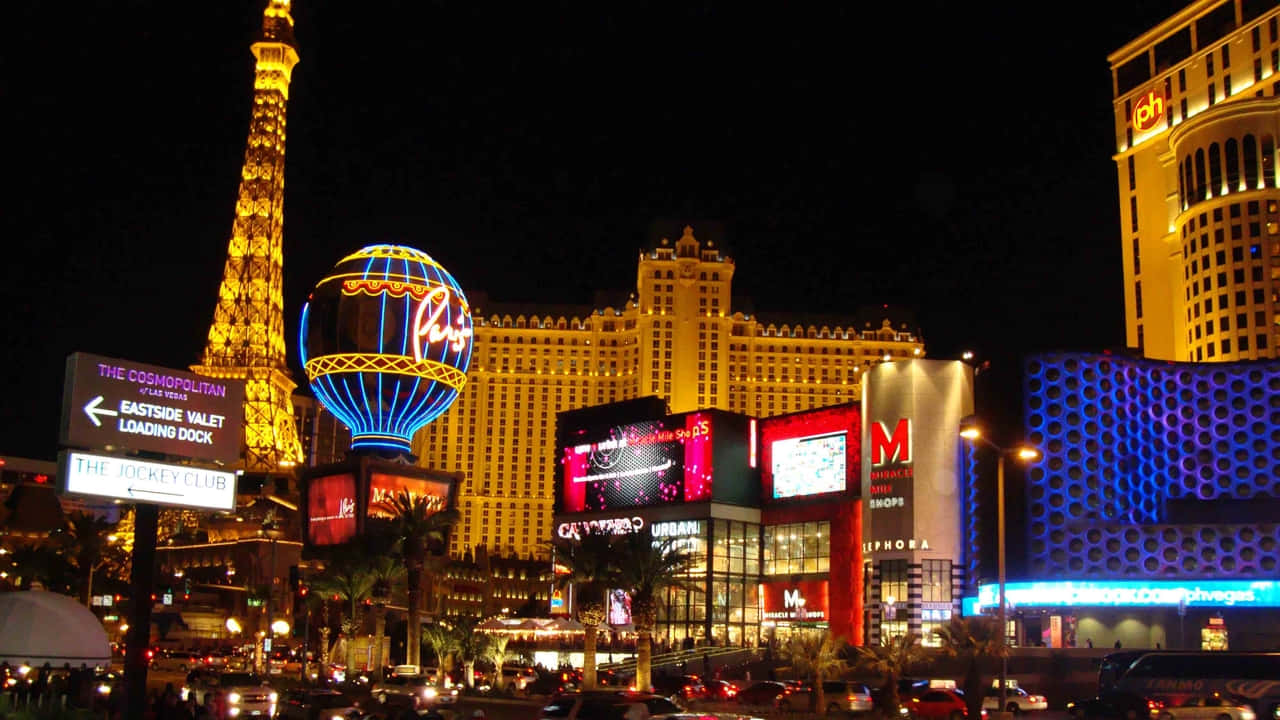 720p Las Vegas 桌布 壁紙 — 充滿活力的霓虹燈照亮了夜晚繁華的拉斯維加斯大道，標誌性酒店和複製的艾菲爾鐵塔在黑暗的天空下閃耀。