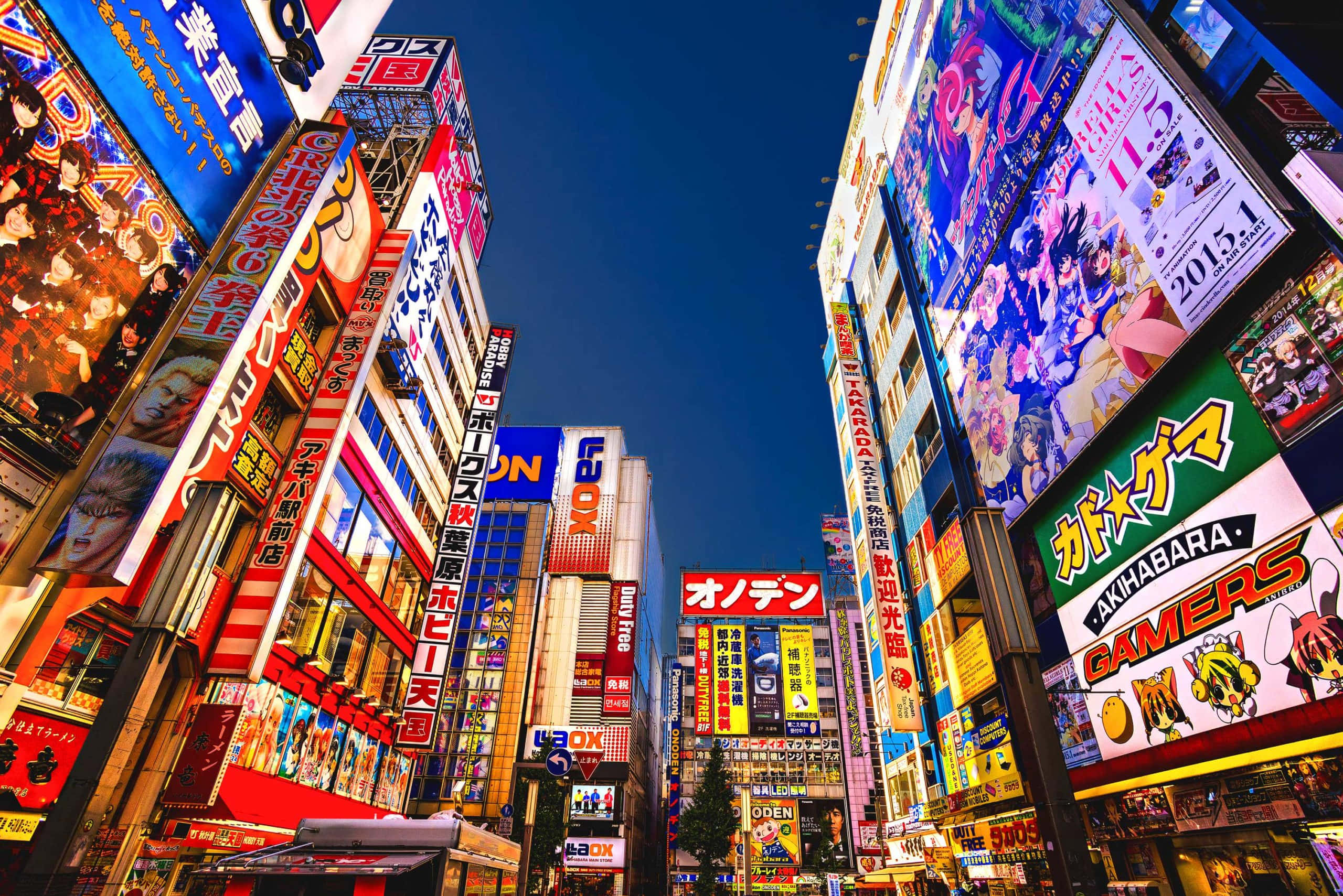 Signs 桌布 壁紙 — 充滿活力的霓虹燈照亮了夜晚繁華的東京街道，高聳的建築物和動漫海報隨處可見。