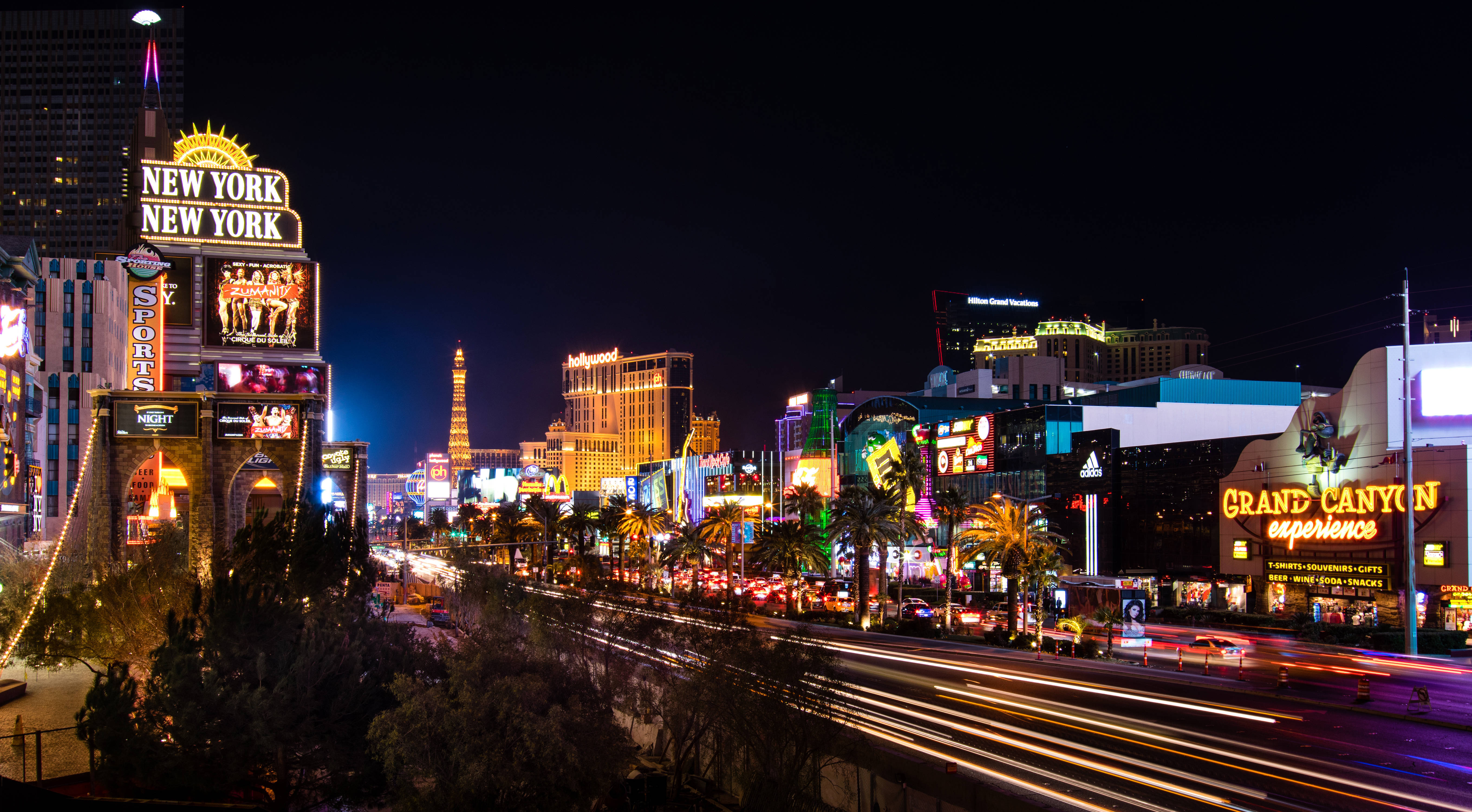 Las Vegas 4K 桌布 壁紙 — 充滿活力的霓虹燈照亮了夜晚繁華的拉斯維加斯大道，伴隨著汽車燈光的流線和標誌性的賭場招牌。