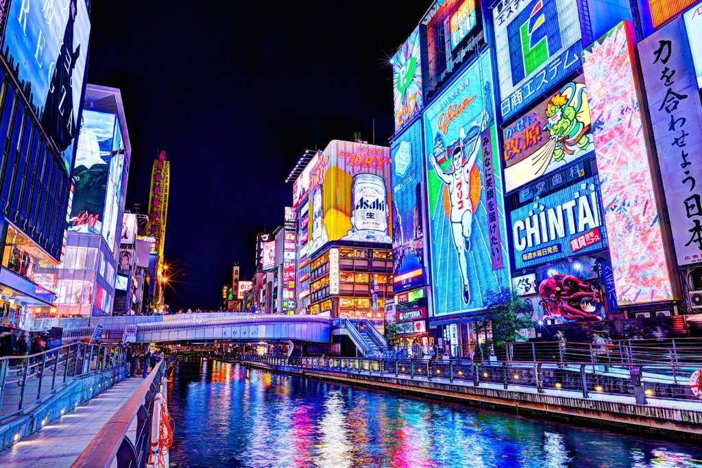 夜間東京運河，發光的霓虹燈倒映在水中。