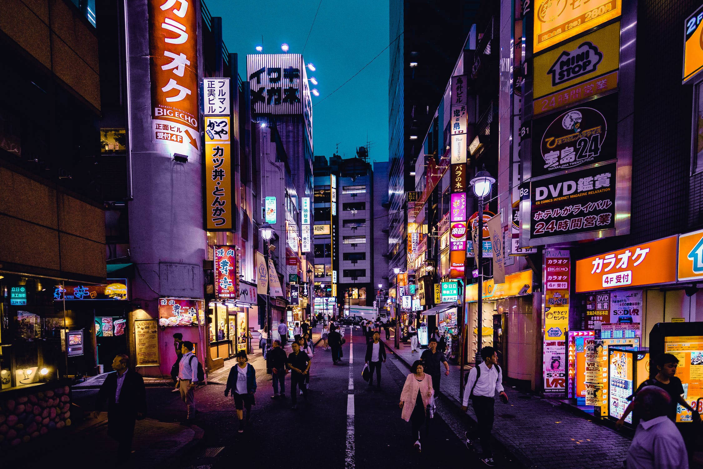 城市 桌布 壁紙 — 充滿活力的霓虹燈照亮了暮色中繁華的東京小巷，行人穿梭在熱鬧的城市峽谷中。