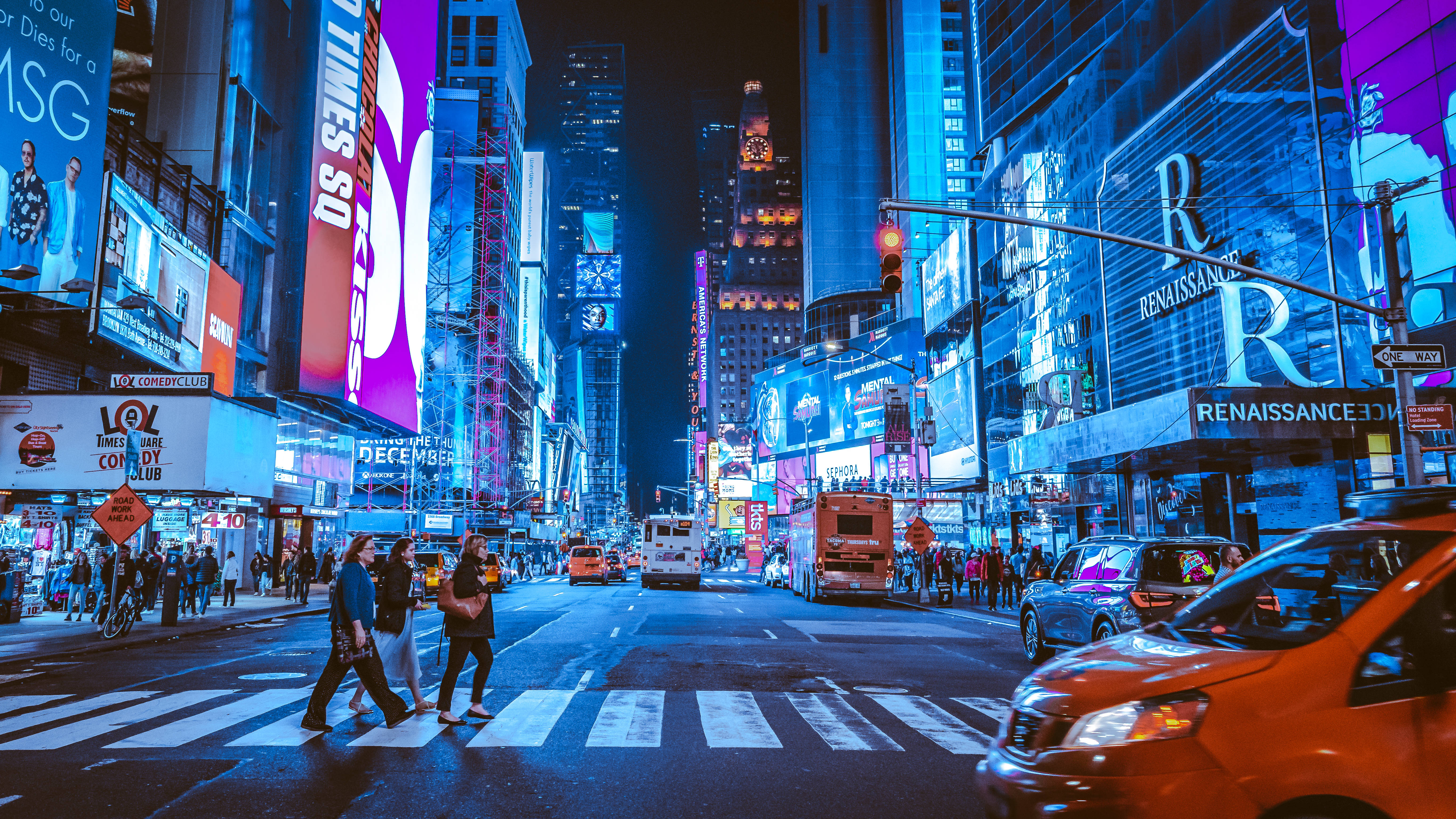 New York 桌布 壁紙 — 充滿活力的霓虹燈照亮了繁忙的紐約市街道，夜晚有行人過馬路和計程車經過。