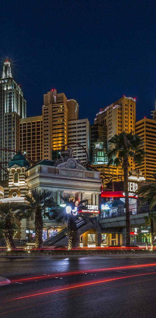 拉斯維加斯之夜 桌布 壁紙 — 充滿活力的霓虹燈照亮了繁華的拉斯維加斯夜景，棕櫚樹和濕漉漉的街道上劃過的車燈。