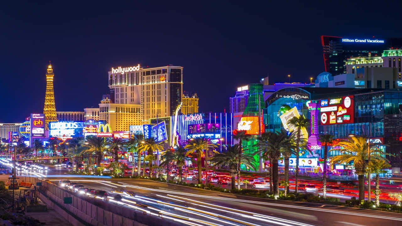 720p Las Vegas 桌布 壁紙 — 充滿活力的霓虹燈照亮了繁華的拉斯維加斯大道夜景，伴隨著流動的車燈和標誌性酒店。
