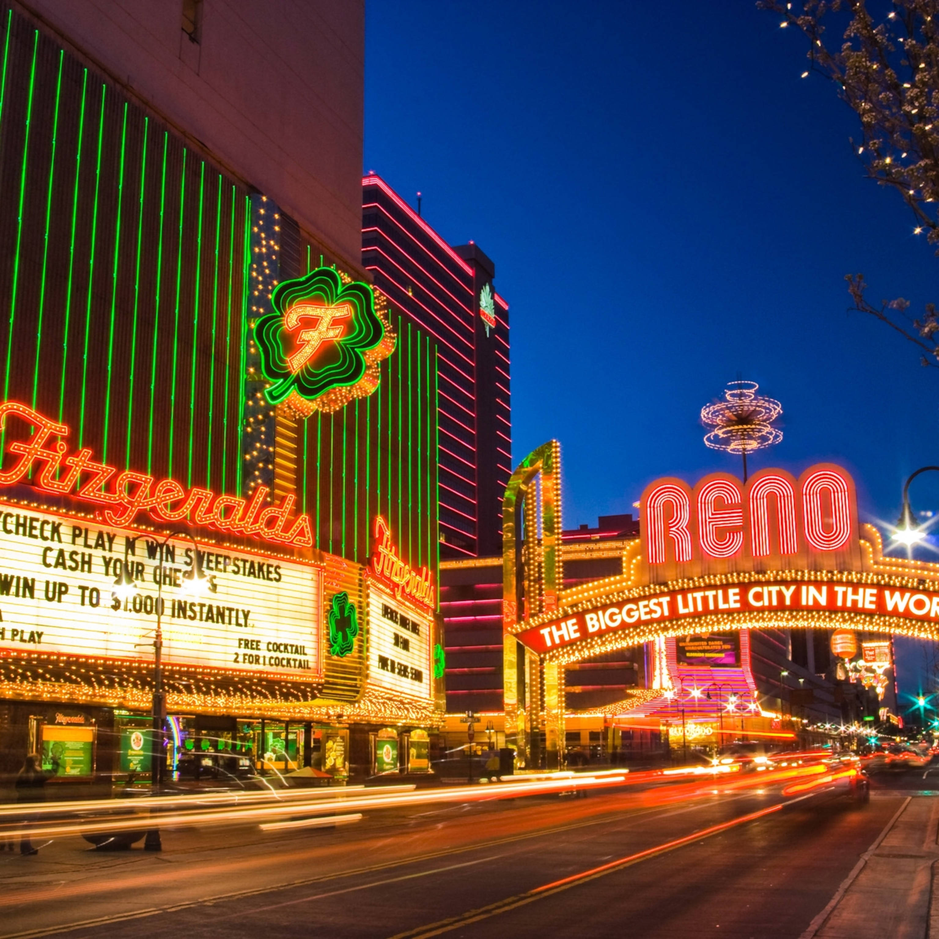 Casino 桌布 壁紙 — 充滿活力的霓虹燈照亮了雷諾繁華的市中心夜景，伴隨著汽車燈光的流線和高聳的賭場招牌。