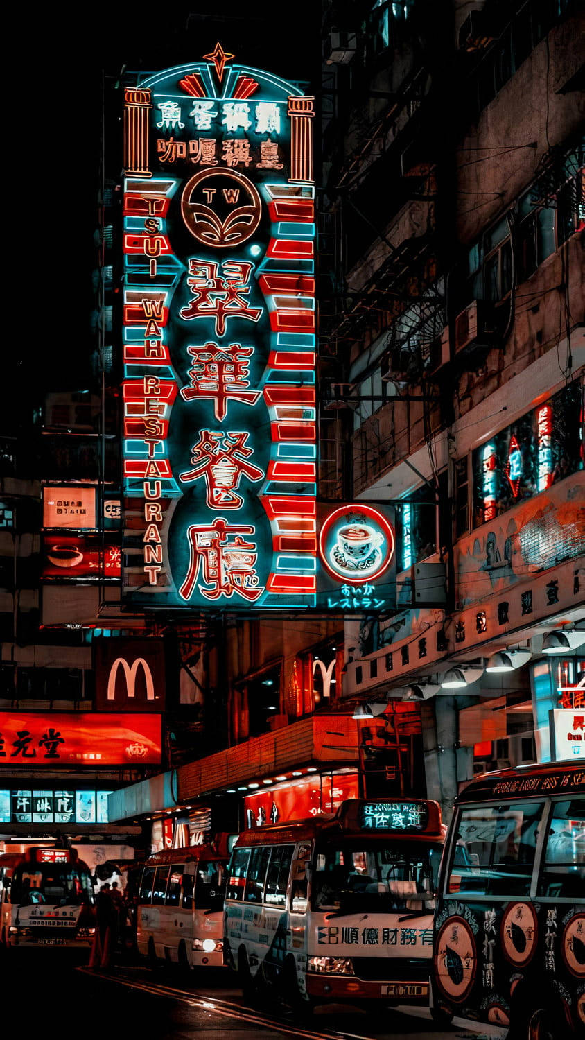 iPhone 桌布 壁紙 — 充滿活力的霓虹燈照亮了香港繁忙的街道，夜晚有色彩繽紛的巴士和高聳的建築物。