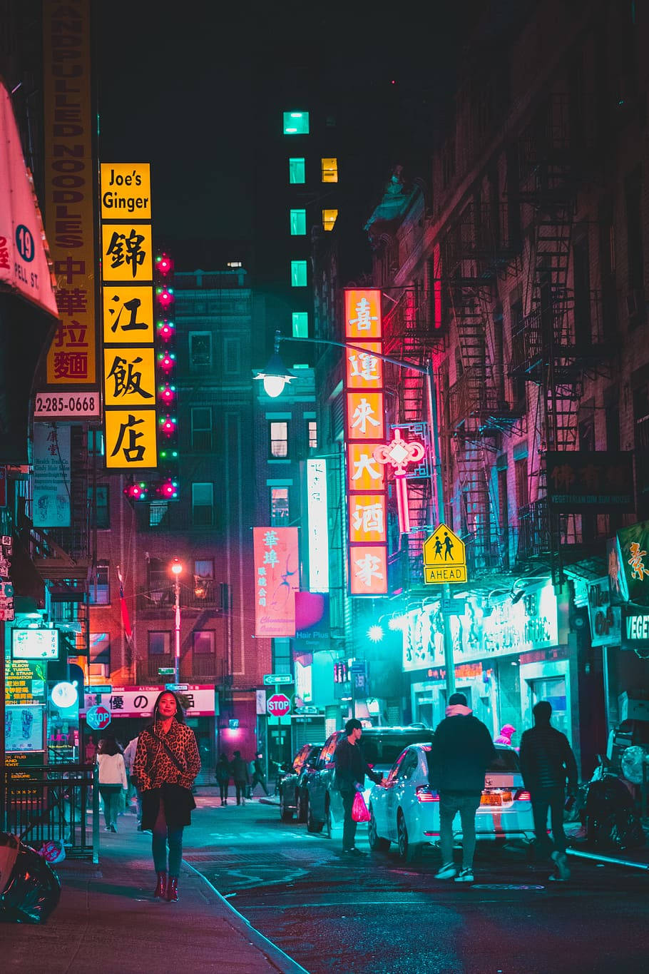 唐人街 桌布 壁紙 — 充滿活力的霓虹燈牌在唐人街繁忙的夜間小巷中閃爍粉紅色和藍綠色，有行人和停泊的汽車。