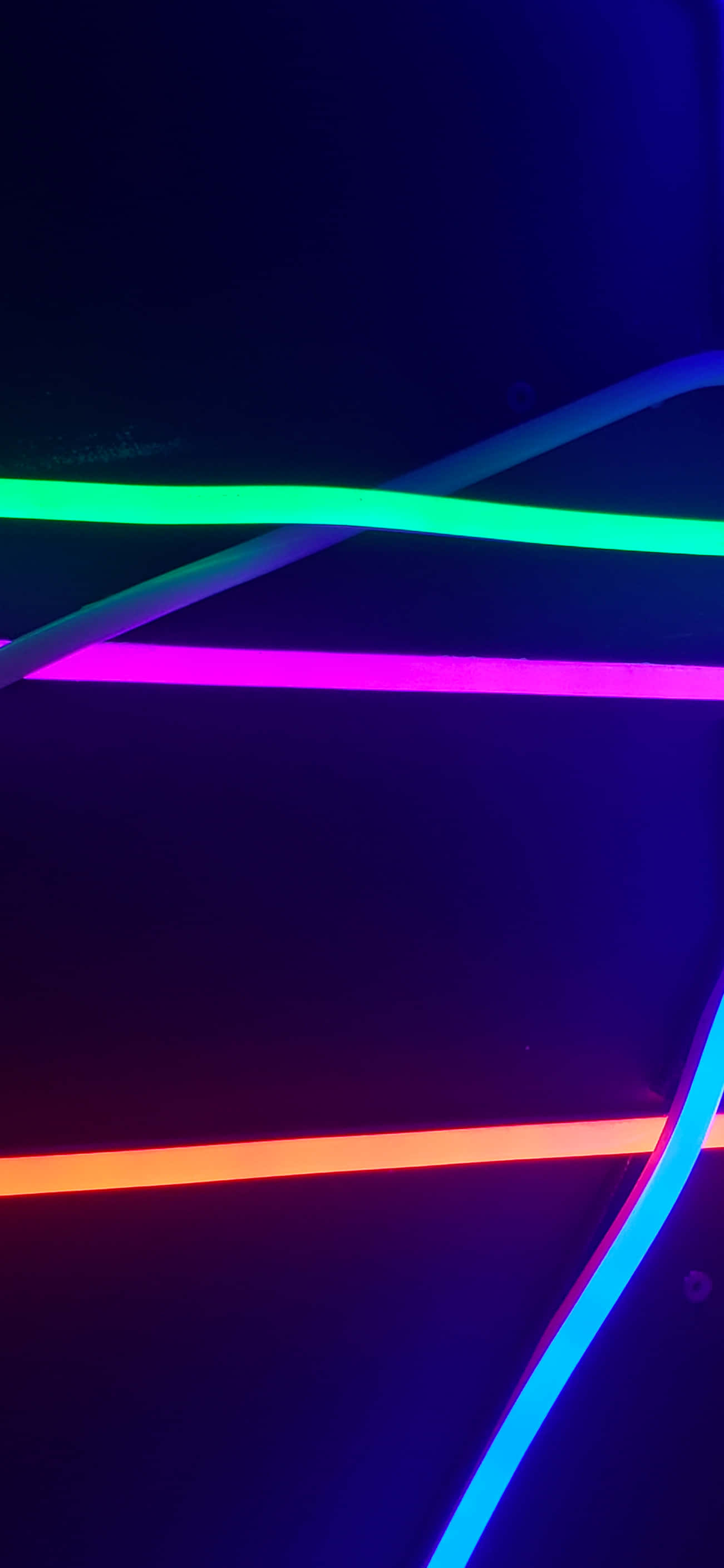 iPhone Neon 桌布 壁紙 — 充滿活力的霓虹燈管以綠色、粉紅色、橙色和藍色在黑暗背景上發光，營造出未來主義的抽象圖案。
