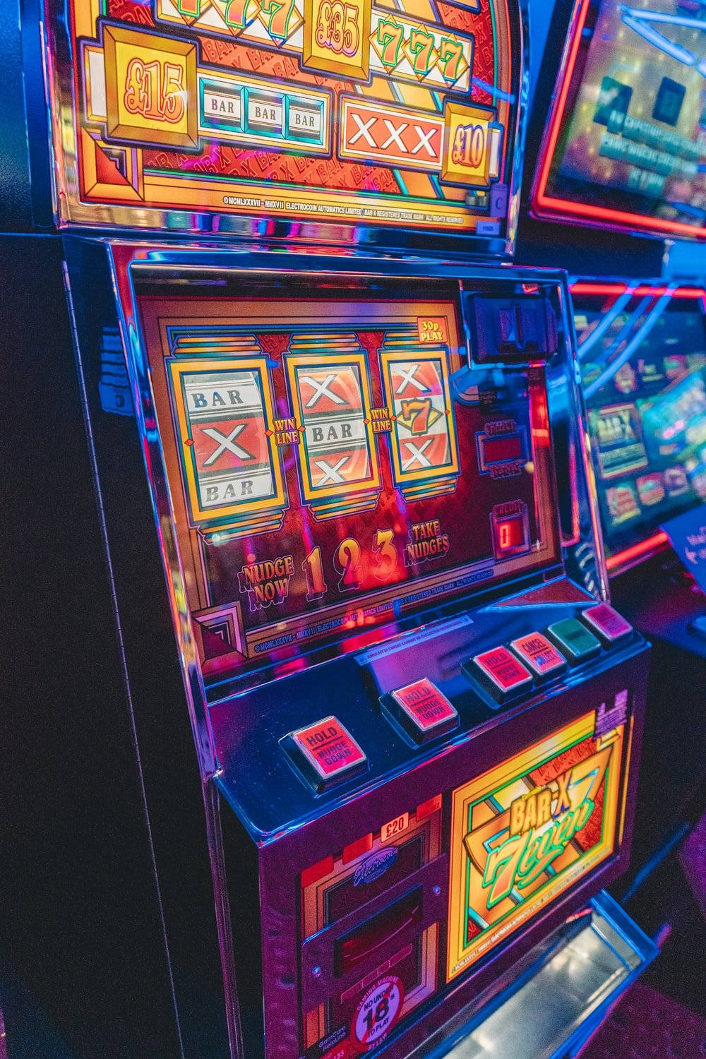 arcade 桌布 壁紙 — 充滿活力的霓虹燈老虎機在昏暗的賭場環境中閃爍著燈光和經典符號。