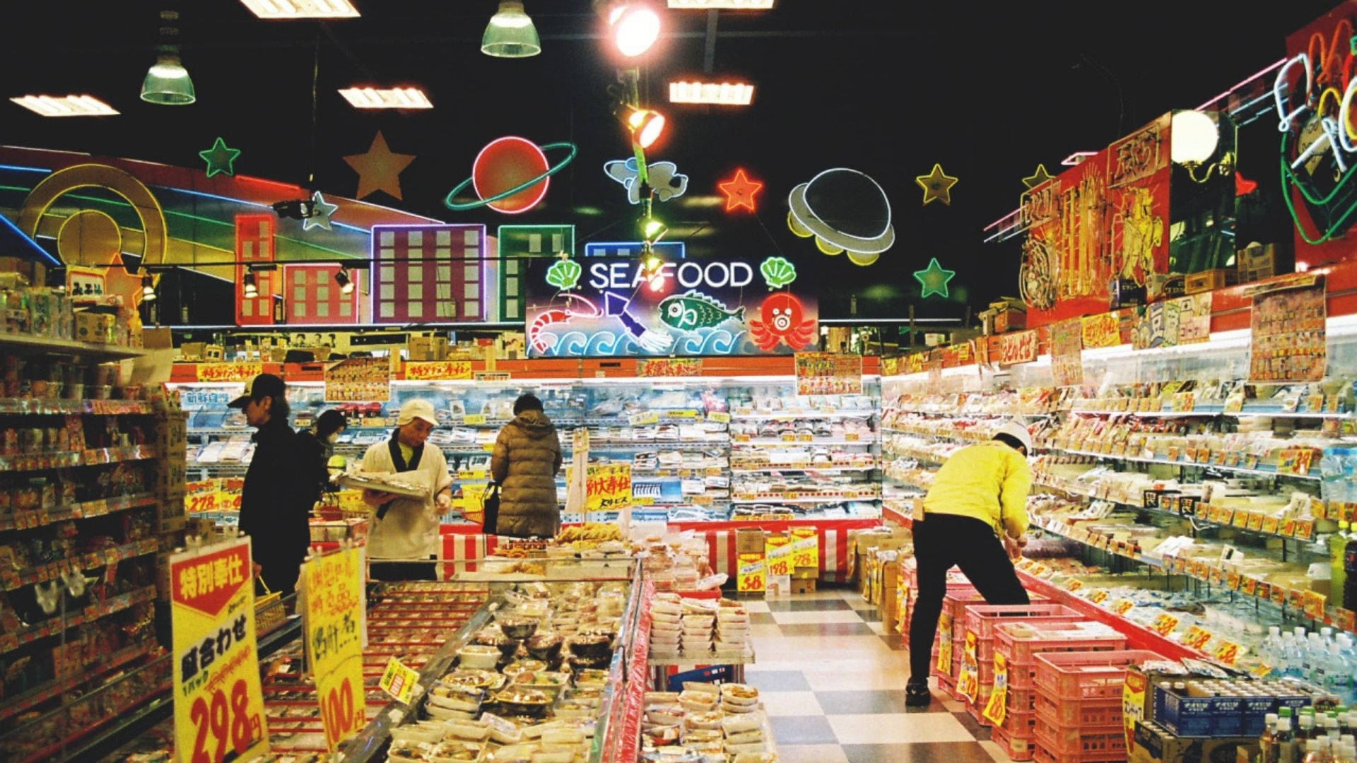 Store 桌布 壁紙 — 充滿活力的霓虹燈超市通道，顧客在色彩繽紛的天花板裝飾下選購海鮮和零食。