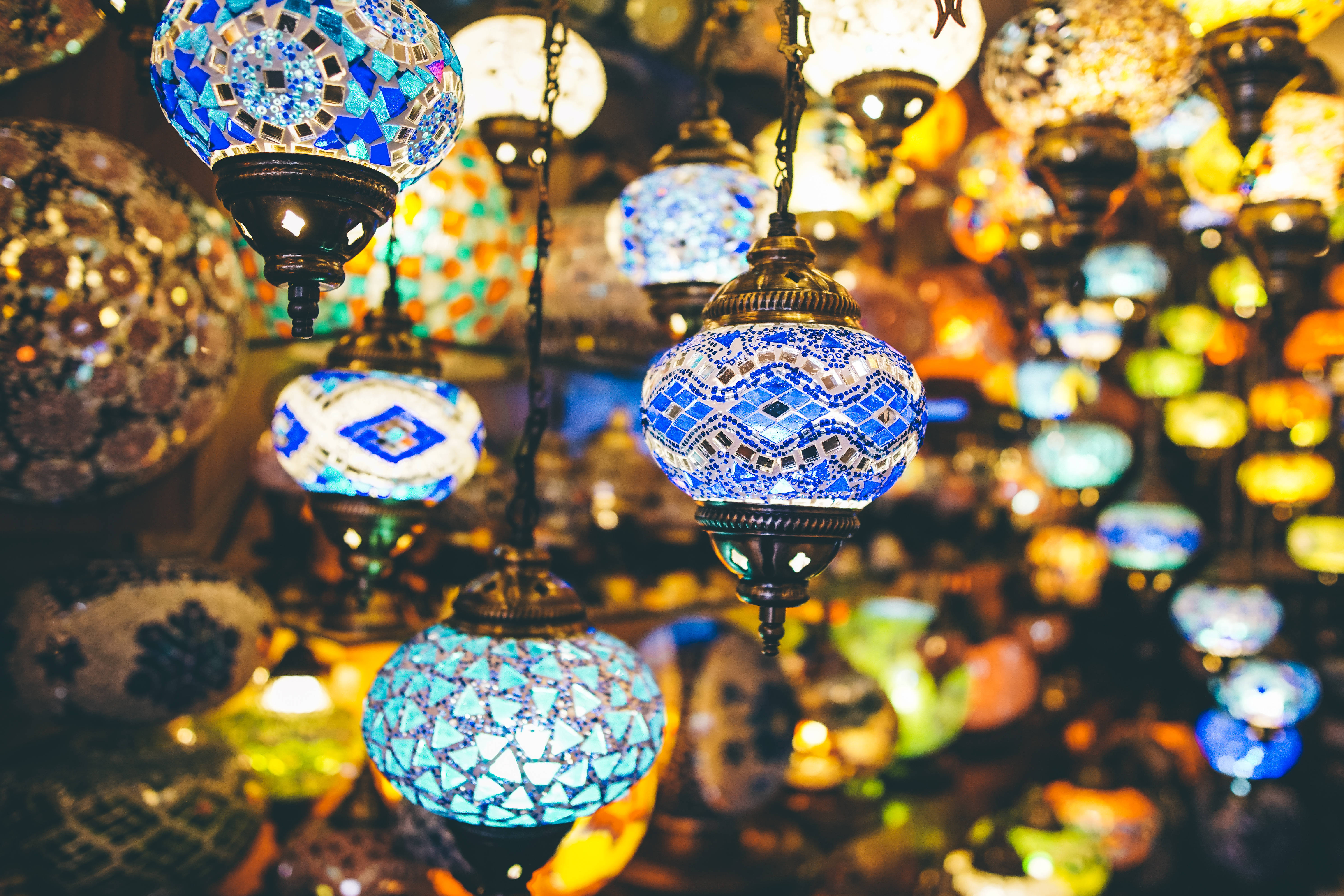 Eid Mubarak 桌布 壁紙 — 充滿活力的馬賽克燈在熙熙攘攘的市集中溫暖地發光，其複雜的藍色和金色圖案捕捉光線。