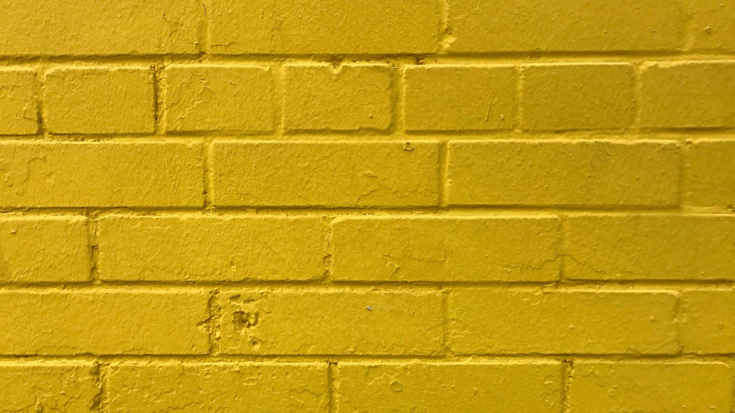 Brick Wall 桌布 壁紙 — 充滿活力的黃色油漆磚牆，特寫鏡頭中可見紋理和砂漿線。