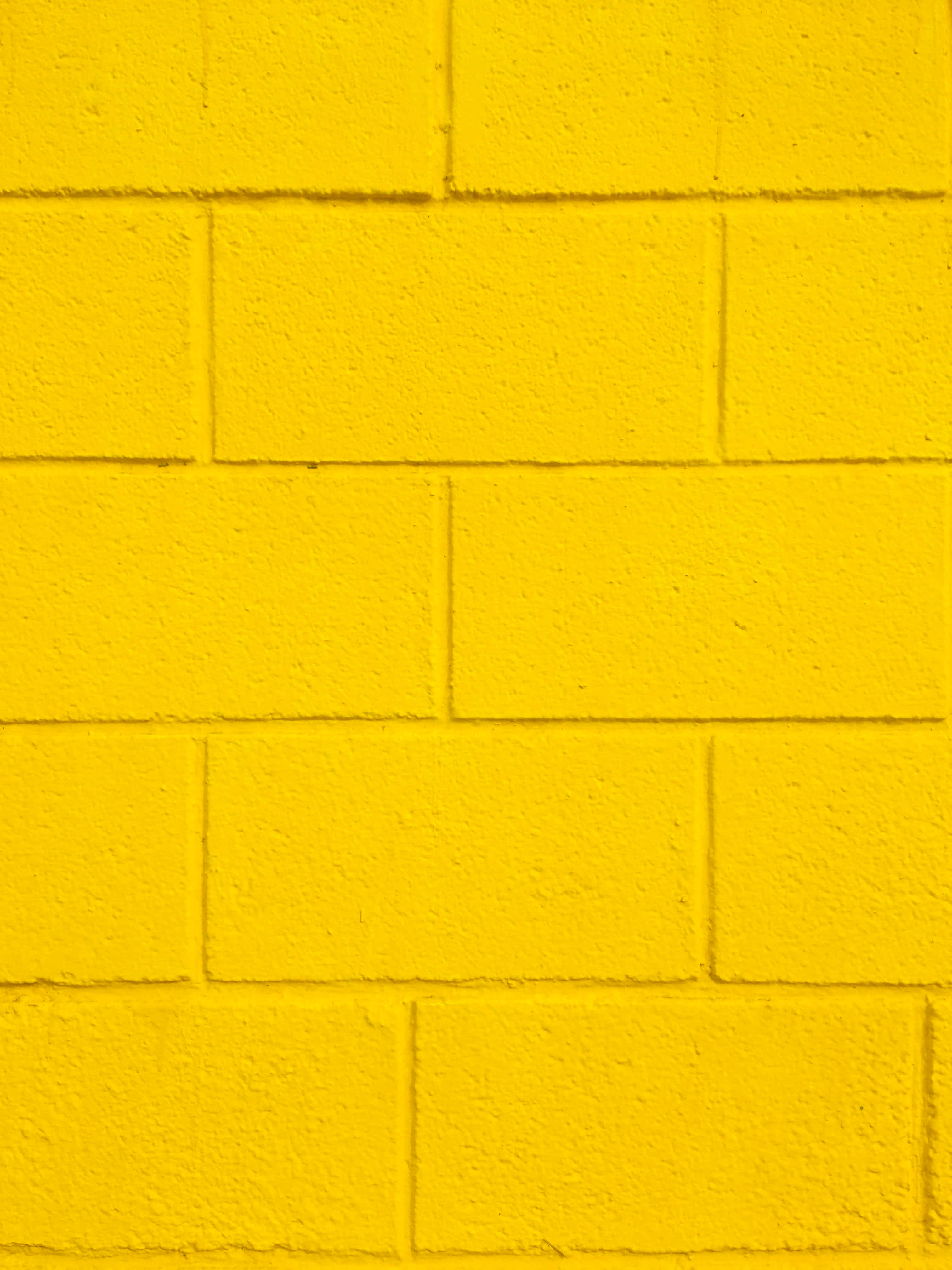 Brick Wall 桌布 壁紙 — 充滿活力的黃色油漆磚牆，表面有紋理，可見砂漿線。