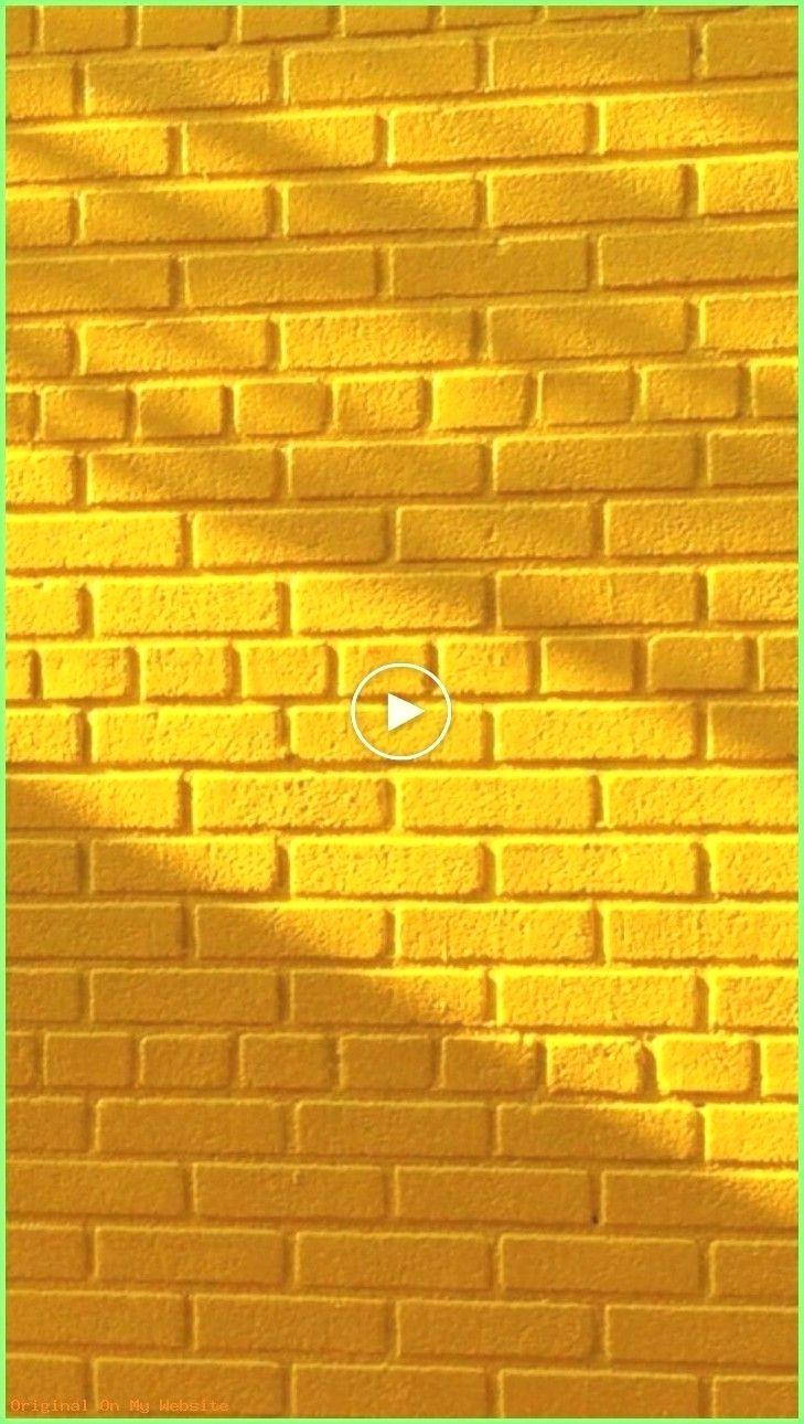 Brick Wall 桌布 壁紙 — 充滿活力的黃色磚牆沐浴在溫暖的陽光下，帶有對角線陰影圖案和中央播放按鈕疊加。