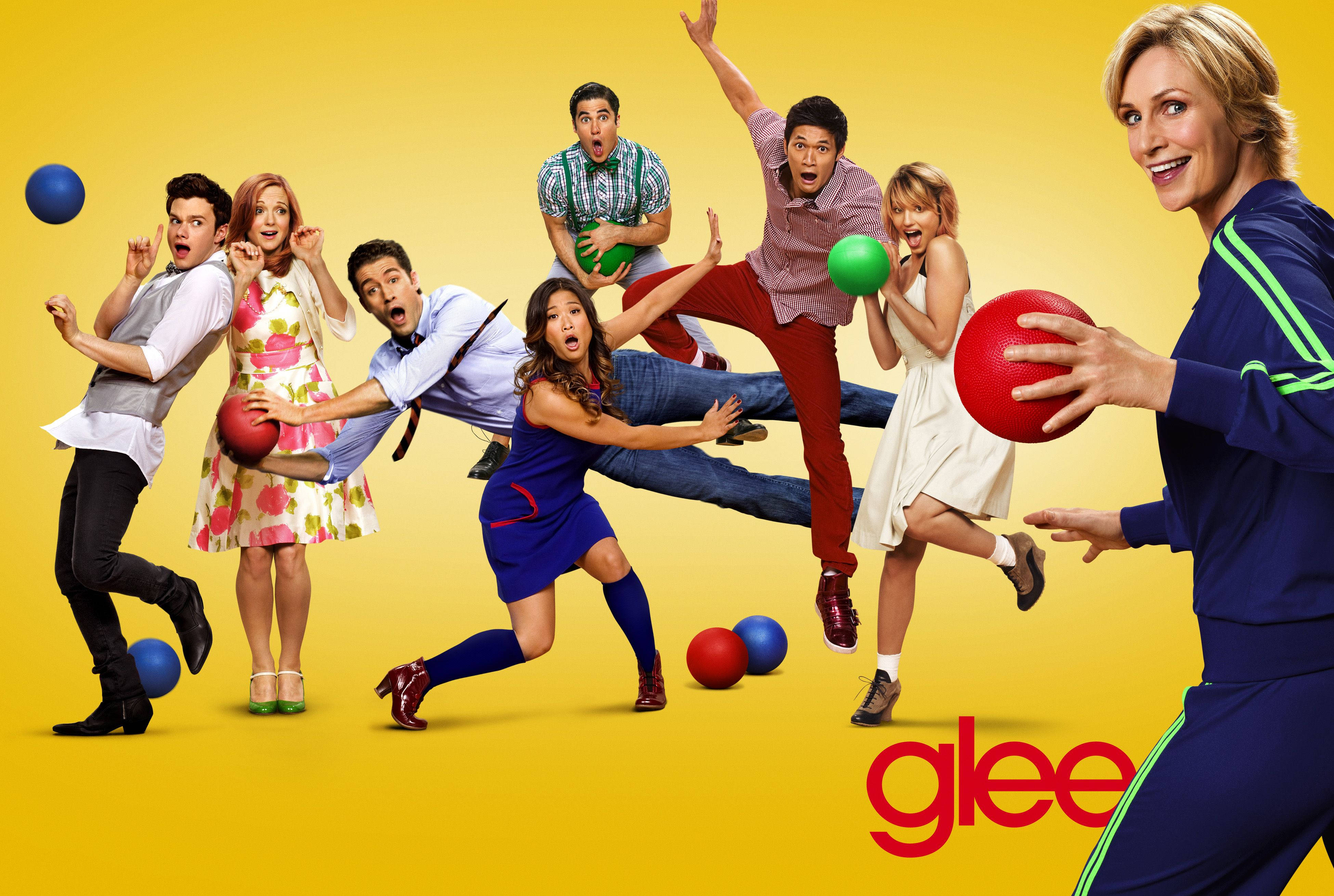 tv 桌布 壁紙 — 充滿活力的黃色背景上，Glee 演員以動態姿勢投擲色彩繽紛的躲避球，表情誇張。
