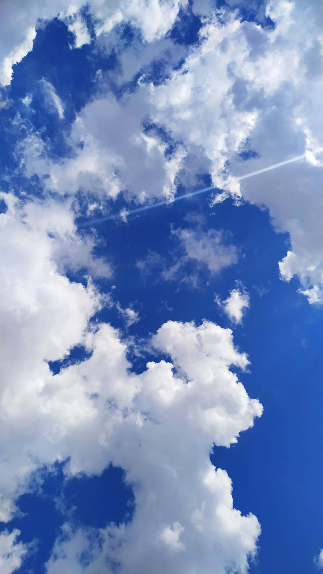 Aesthetic Cloud 桌布 壁紙 — 充滿蓬鬆白雲的鮮豔藍天，一道明亮的陽光穿透而過。