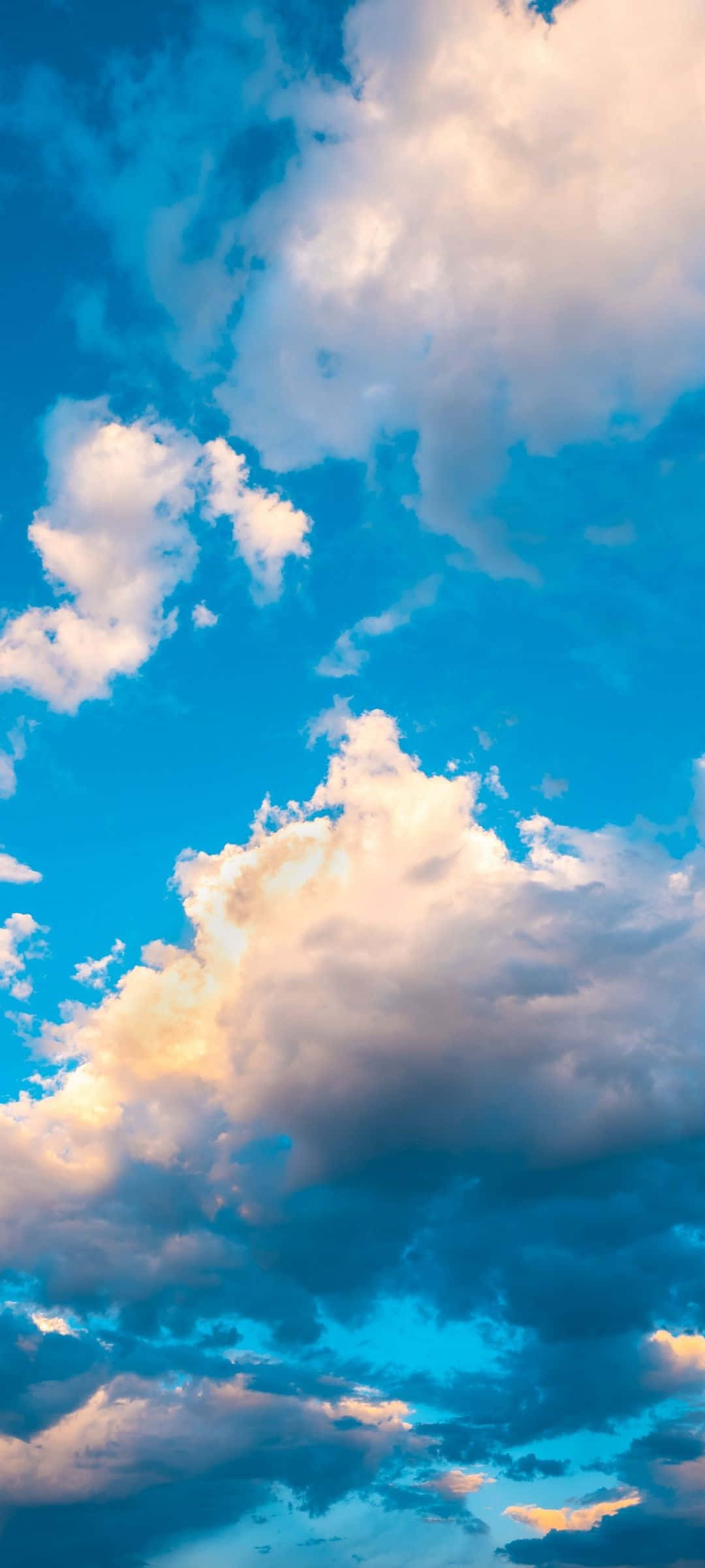 桌布 壁紙 — 充滿蓬鬆白雲的鮮豔藍天，在金色夕陽下閃耀。