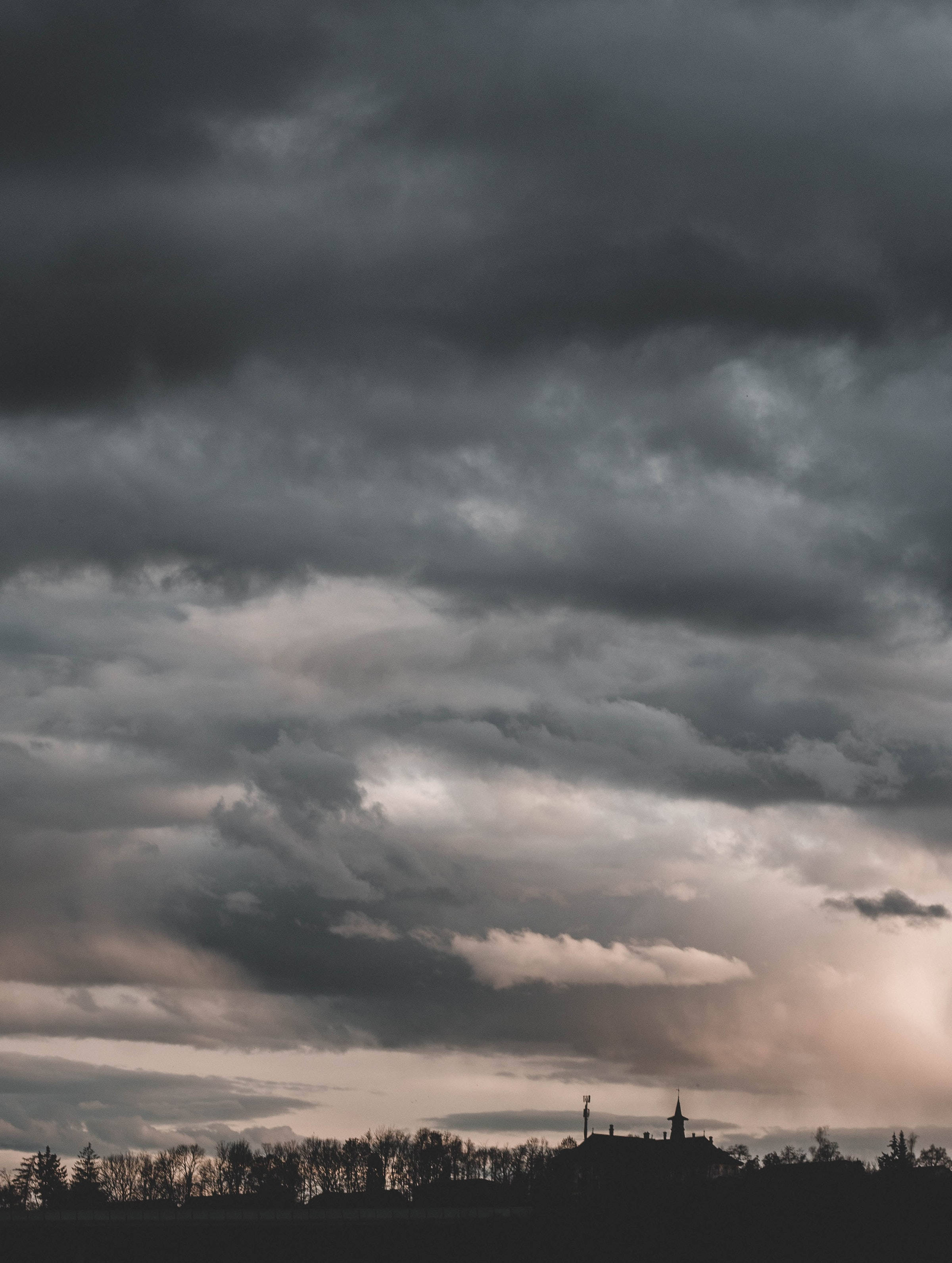 雲朵 桌布 壁紙 — 充滿黑暗暴風雲的戲劇性天空籠罩著黃昏時分的教堂和樹木剪影。