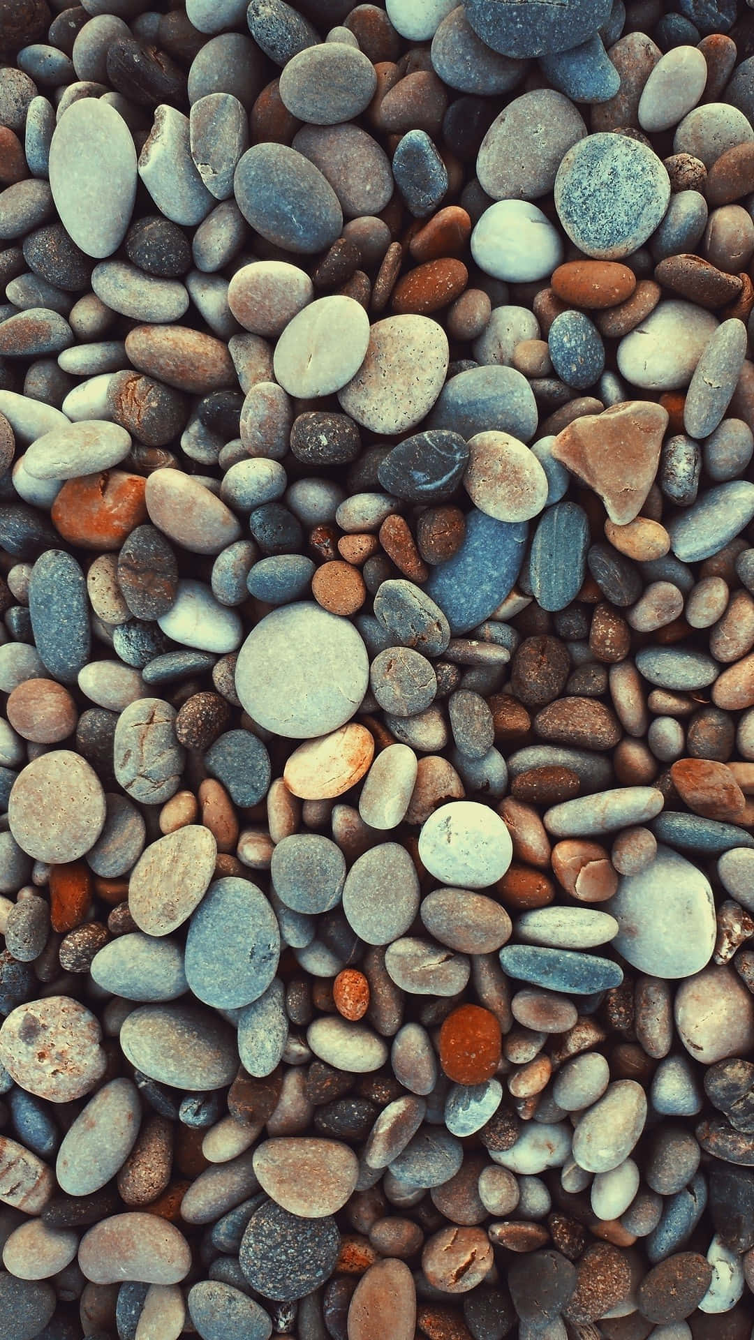 Stone 桌布 壁紙 — 光滑圓潤卵石的近距離特寫，呈現藍灰色、棕色和橙色的泥土色調。