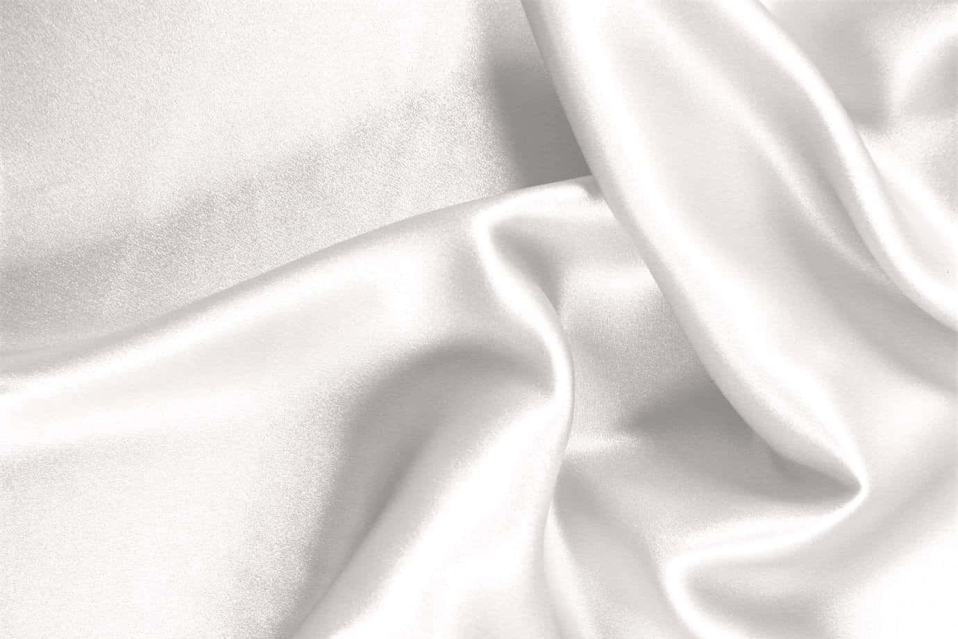 White Silk 桌布 壁紙 — 光滑白色緞面布料特寫，柔軟皺褶捕捉柔和光線。