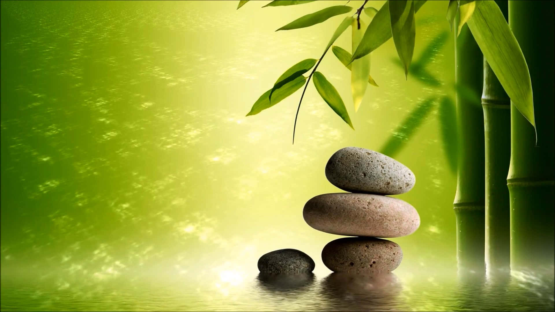 禪 桌布 壁紙 — 光滑的石頭堆疊在反射的水面上，旁邊是發光的竹莖，沐浴在柔和的金色光線下。