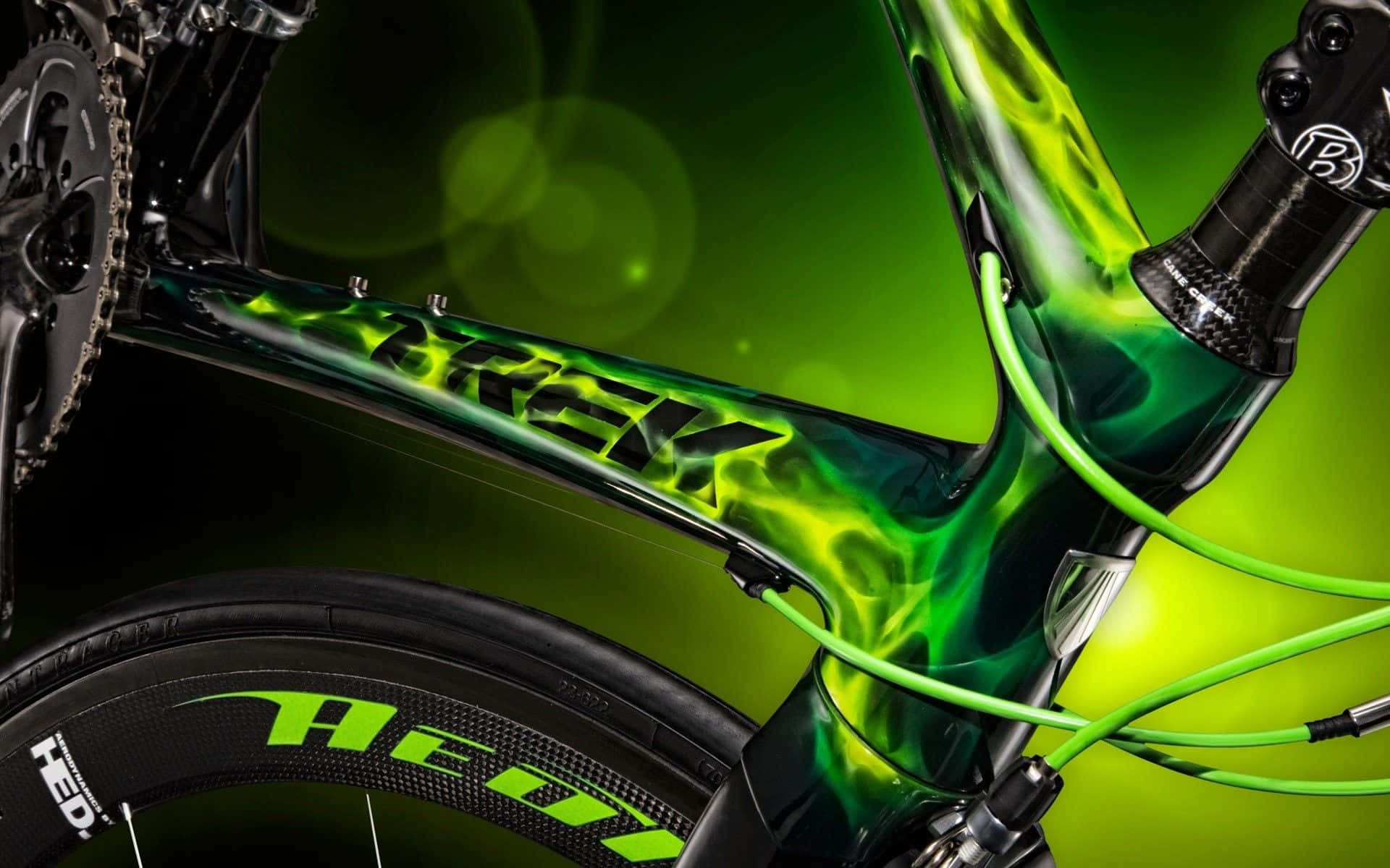 Bikes 桌布 壁紙 — 光滑黑色Trek自行車車架的特寫，帶有充滿活力的綠色火焰貼花和匹配的綠色電纜，背景為發光的綠色。