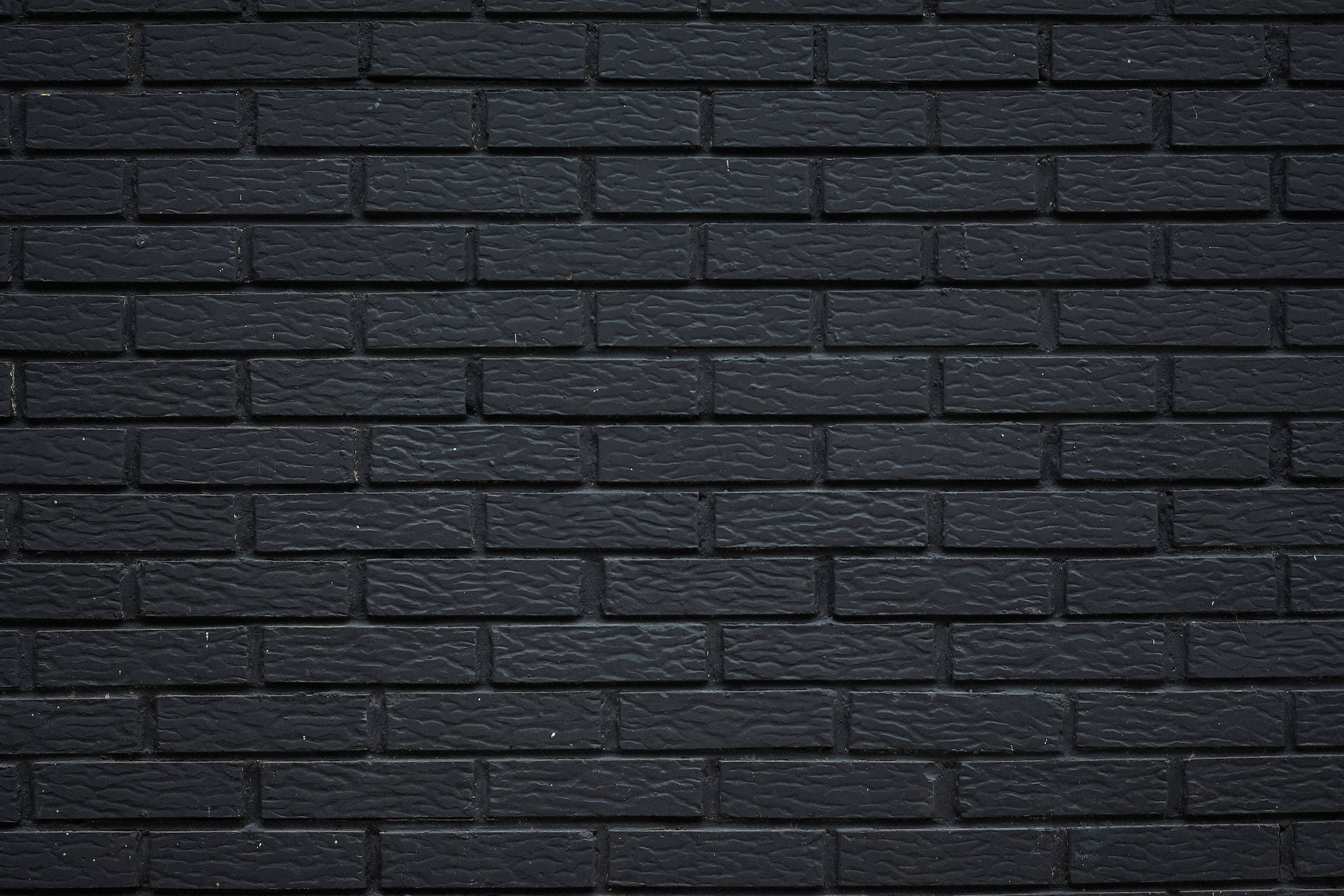 Brick Wall 桌布 壁紙 — 光滑黑色磚牆的近距離特寫，帶有紋理灰泥線條和微妙的灰色亮點。