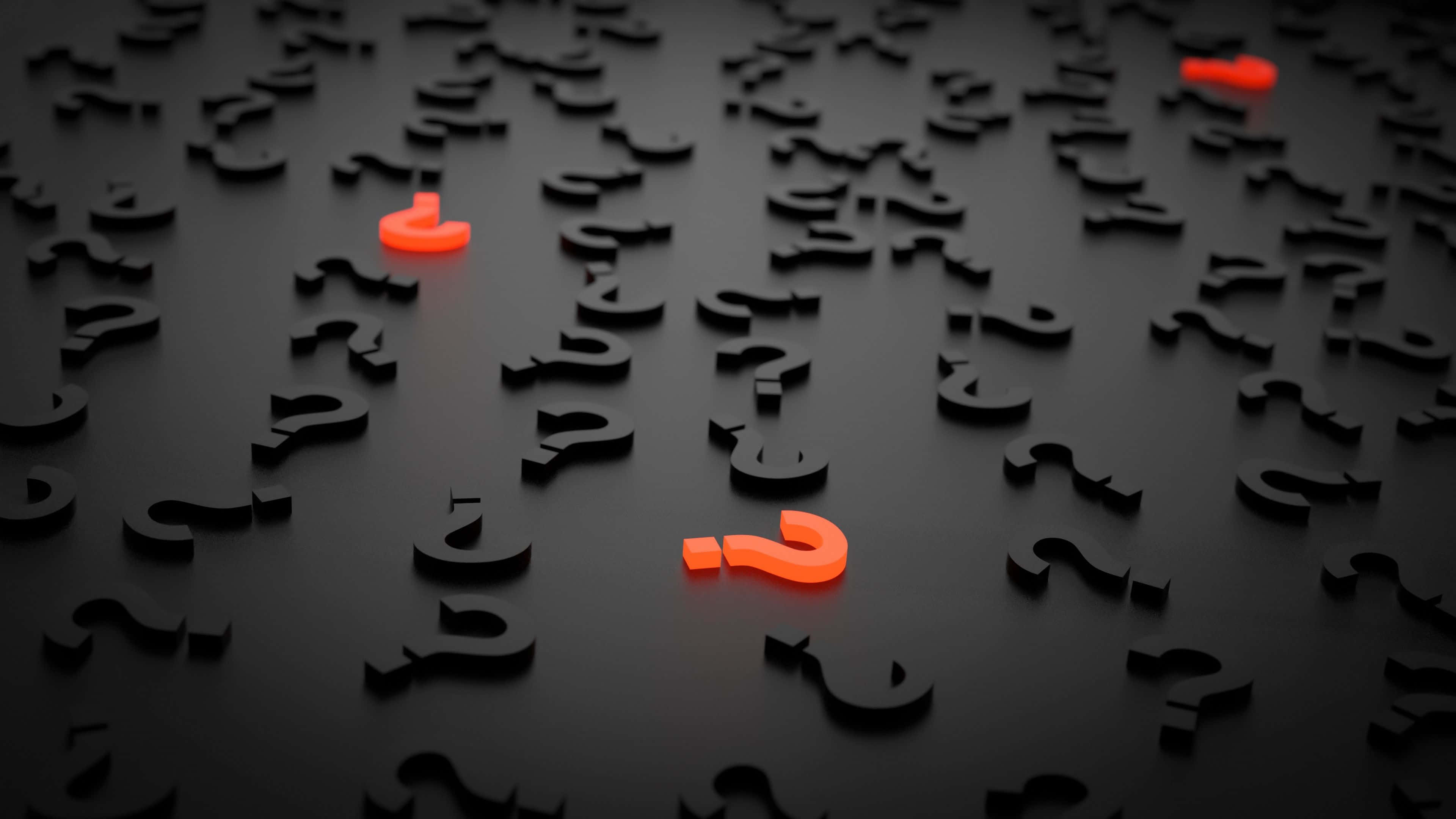 Question 桌布 壁紙 — 光滑黑色表面上散落著在聚光燈下發出橙色光芒的3D問號。