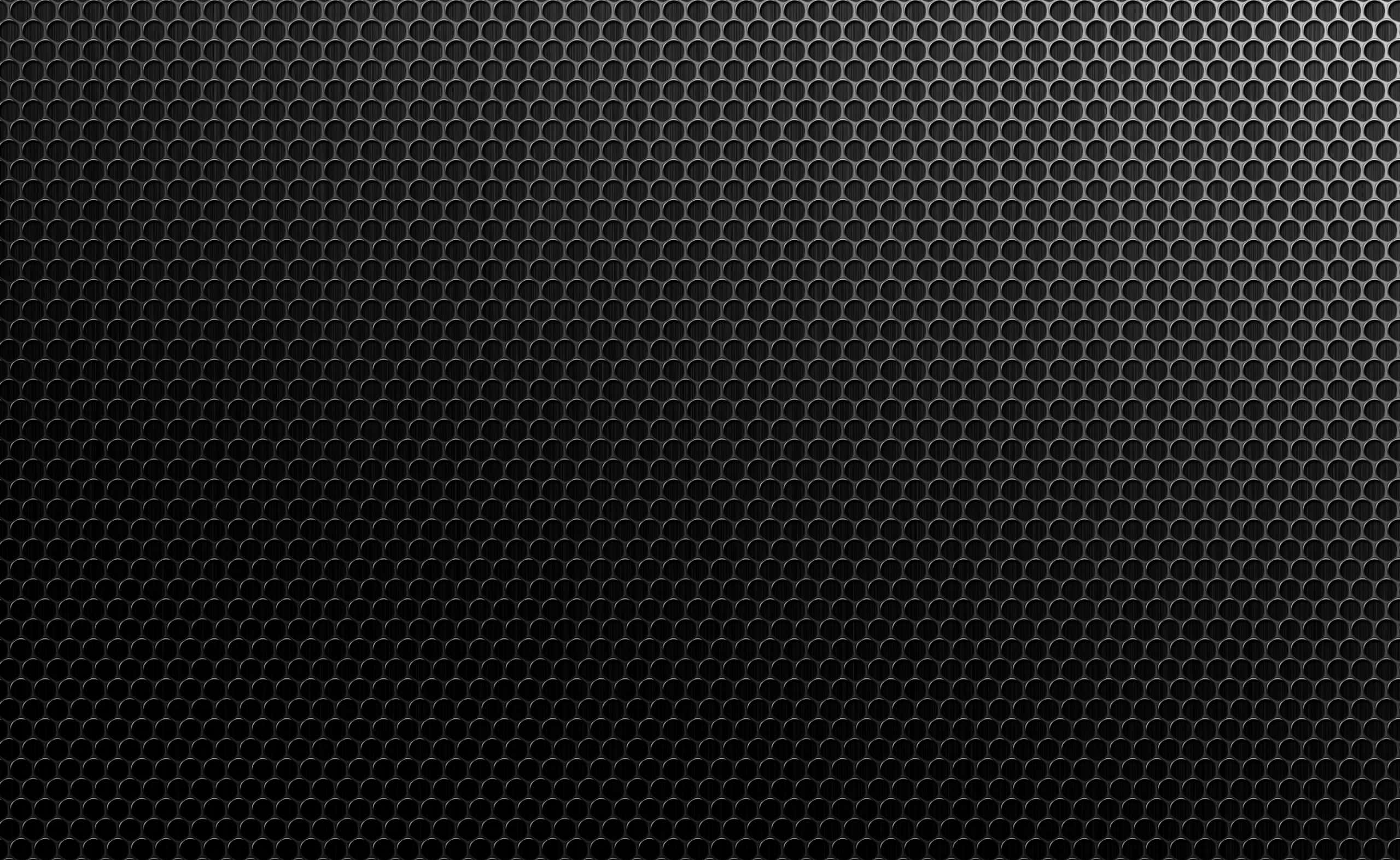 Dark Texture 桌布 壁紙 — 光滑黑色金屬表面，帶有重複的六角形穿孔圖案和微妙的漸變照明。