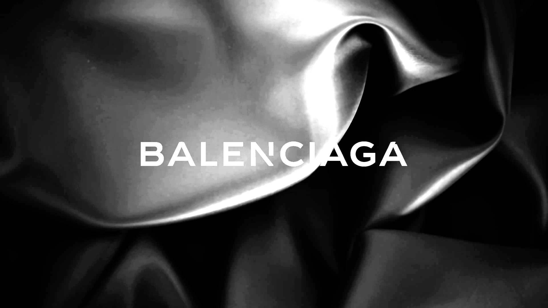 Balenciaga 桌布 壁紙 — 光澤布料皺褶的黑白特寫，帶有粗體白色文字 Balenciaga。