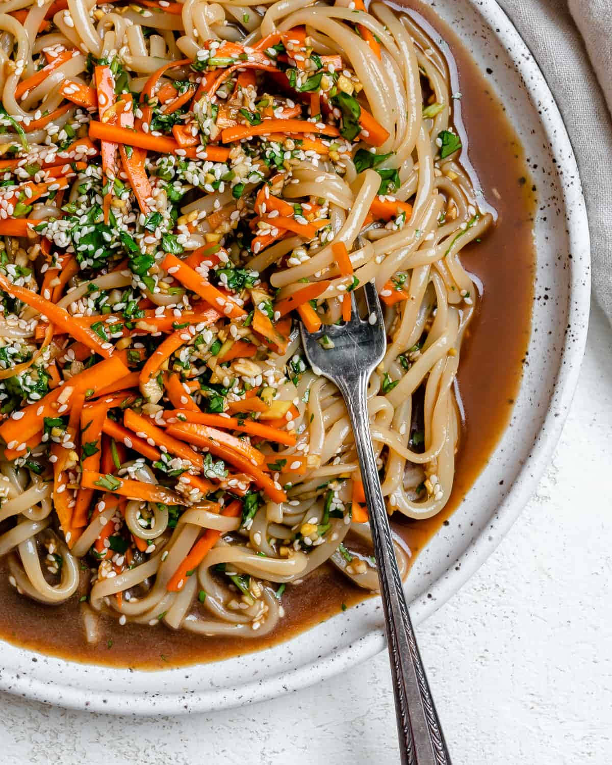 Noodles 桌布 壁紙 — 光澤烏龍麵配上美味醬汁，上面撒有紅蘿蔔絲、芝麻和切碎香草，盛在斑點碗中的特寫。
