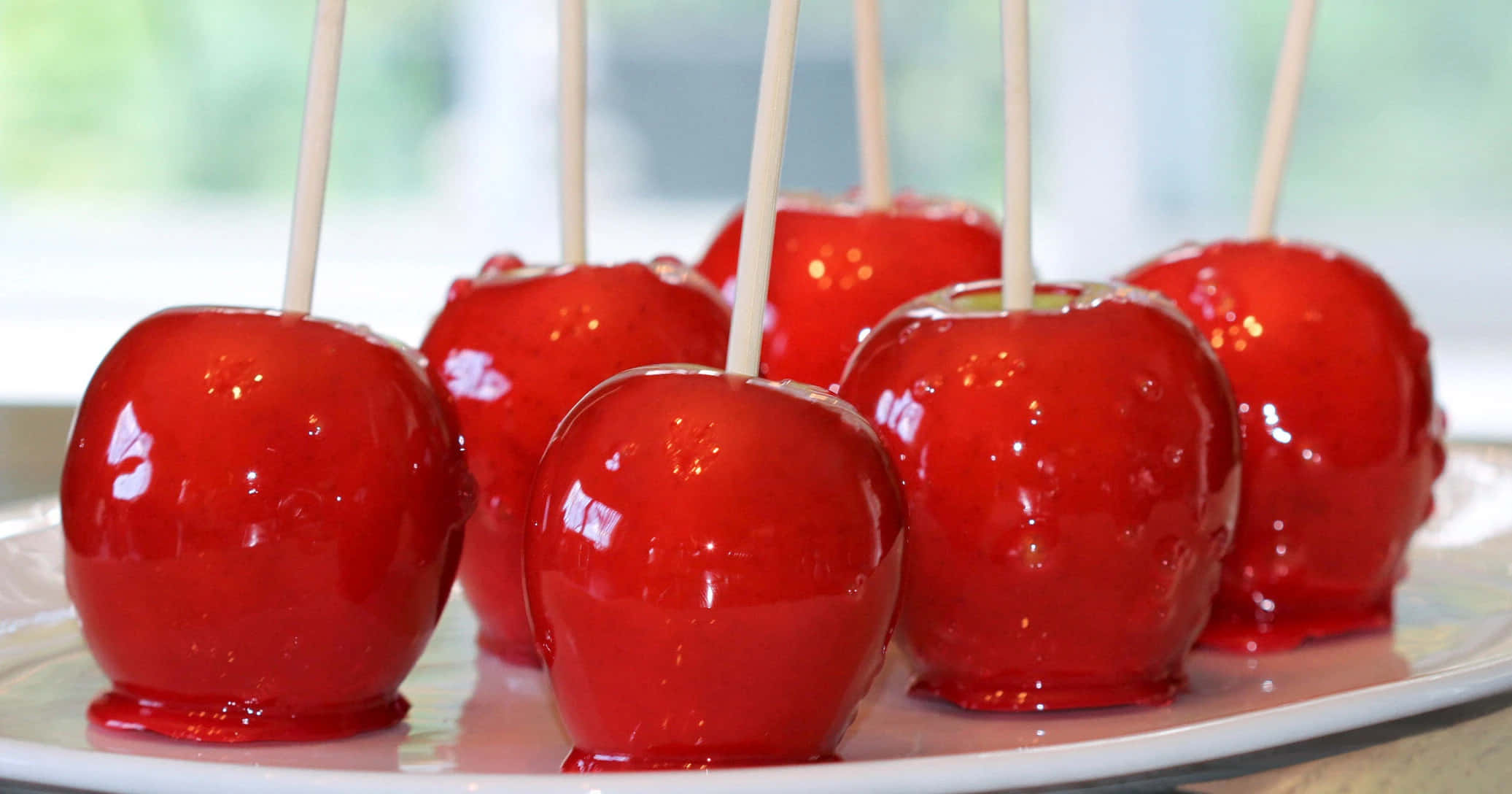 Candy Apples 桌布 壁紙 — 光澤的紅色糖蘋果串在白色盤子上排列，柔和自然光凸顯其糖衣光澤。