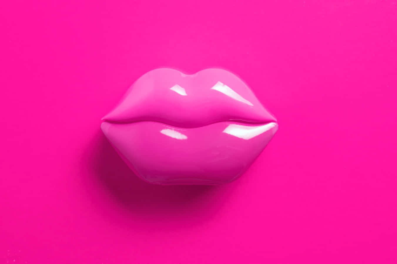 Pink Lipstick 桌布 壁紙 — 光澤粉紅唇雕塑置於充滿活力的紫紅色背景中央，帶有柔和陰影。