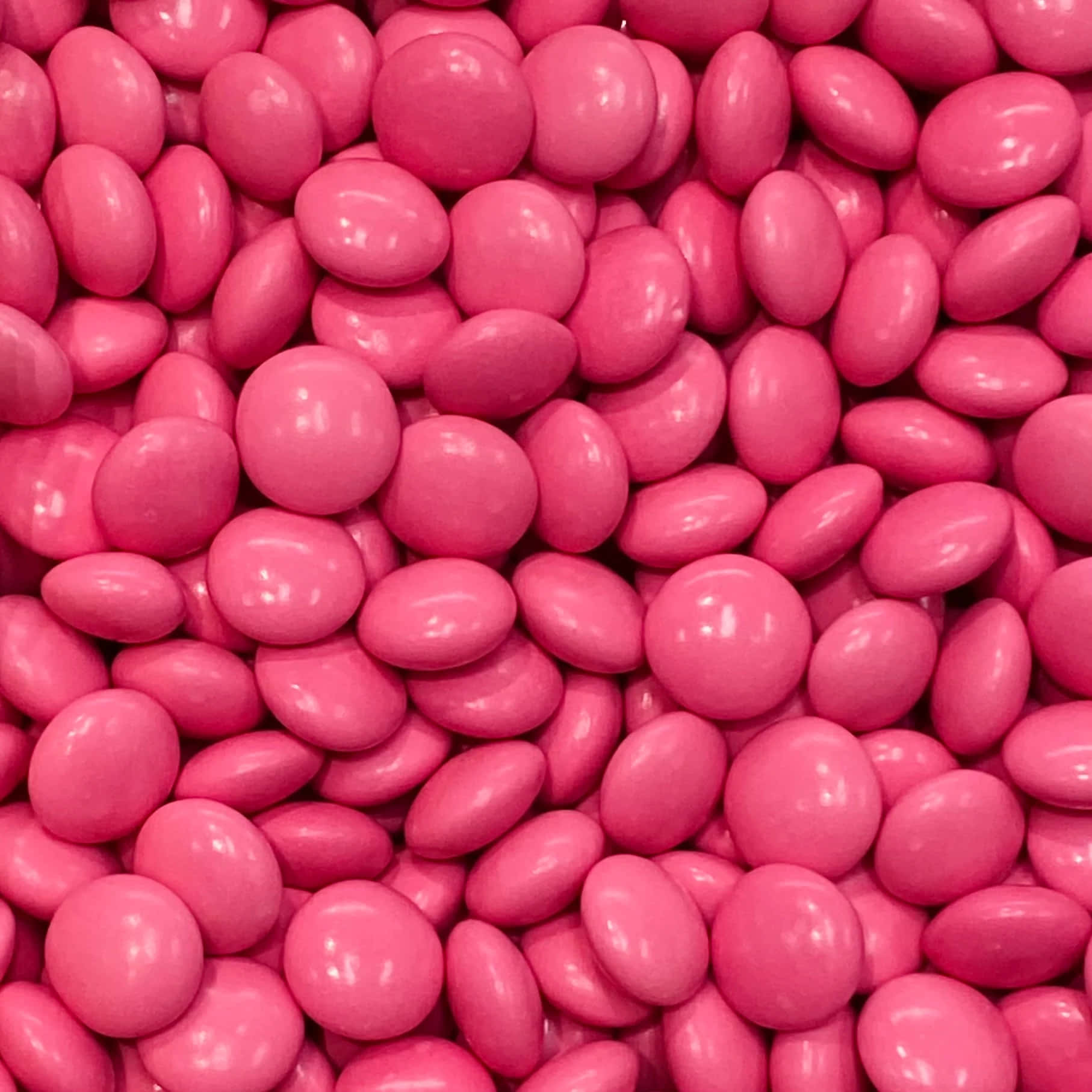 Pink Candy 桌布 壁紙 — 光澤粉紅色糖果塗層巧克力緊密堆疊的特寫，帶有反射高光。