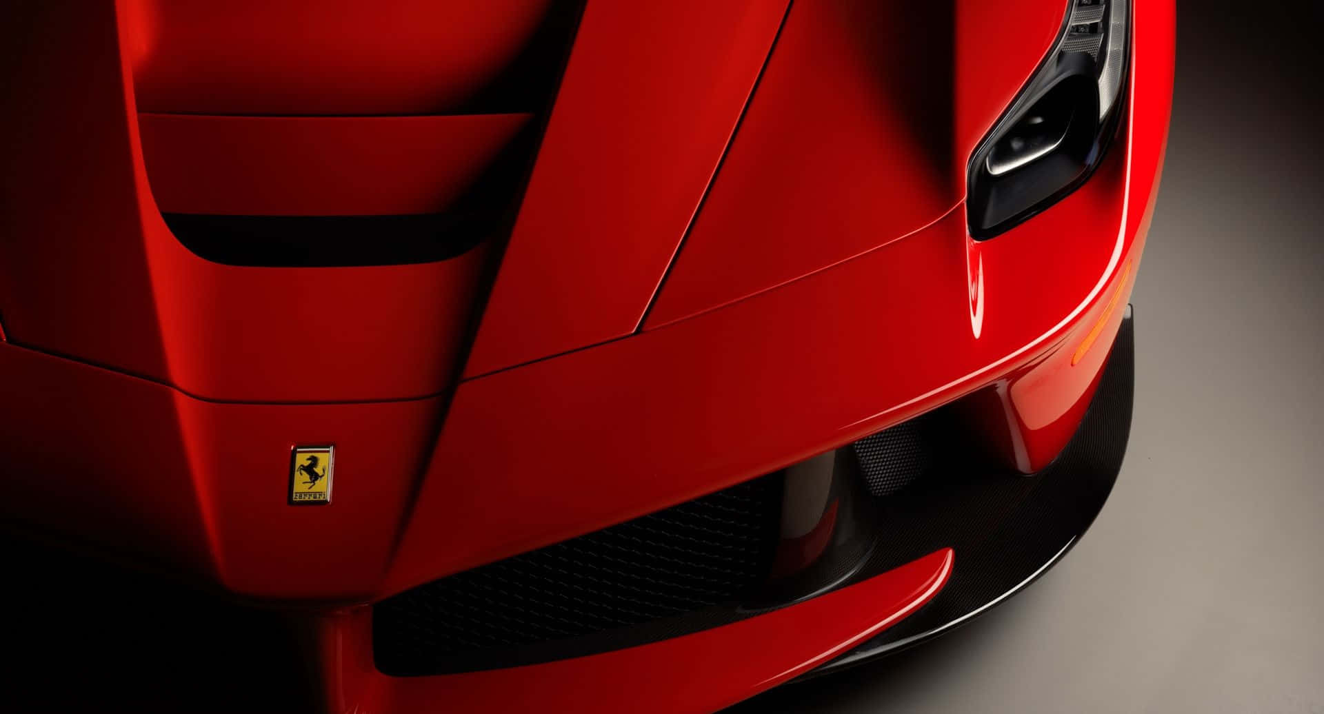 Ferrari Laferrari 桌布 壁紙 — 光澤紅色法拉利跑車前保險桿和引擎蓋的特寫，帶有黑色格柵和標誌性的躍馬標誌。