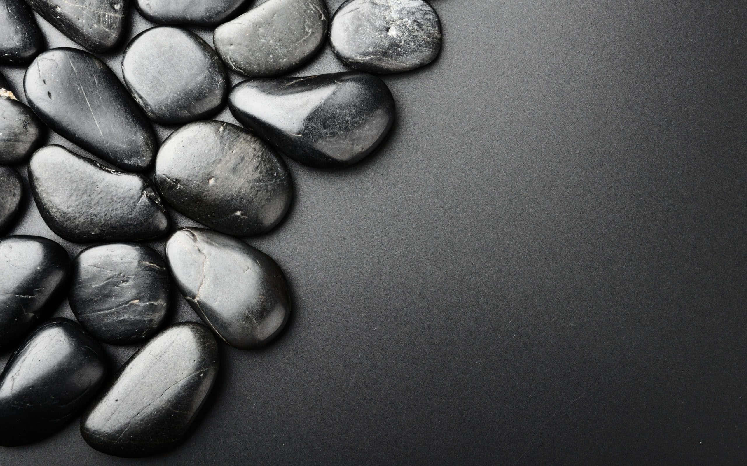 Stone 桌布 壁紙 — 光澤黑色河石聚集在啞光深灰色表面的角落。