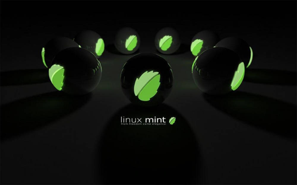 Linux 桌布 壁紙 — 光澤黑色球體上帶有發光綠色葉子標誌，排列成圓形，位於深色表面上，下方有 Linux Mint 標誌。