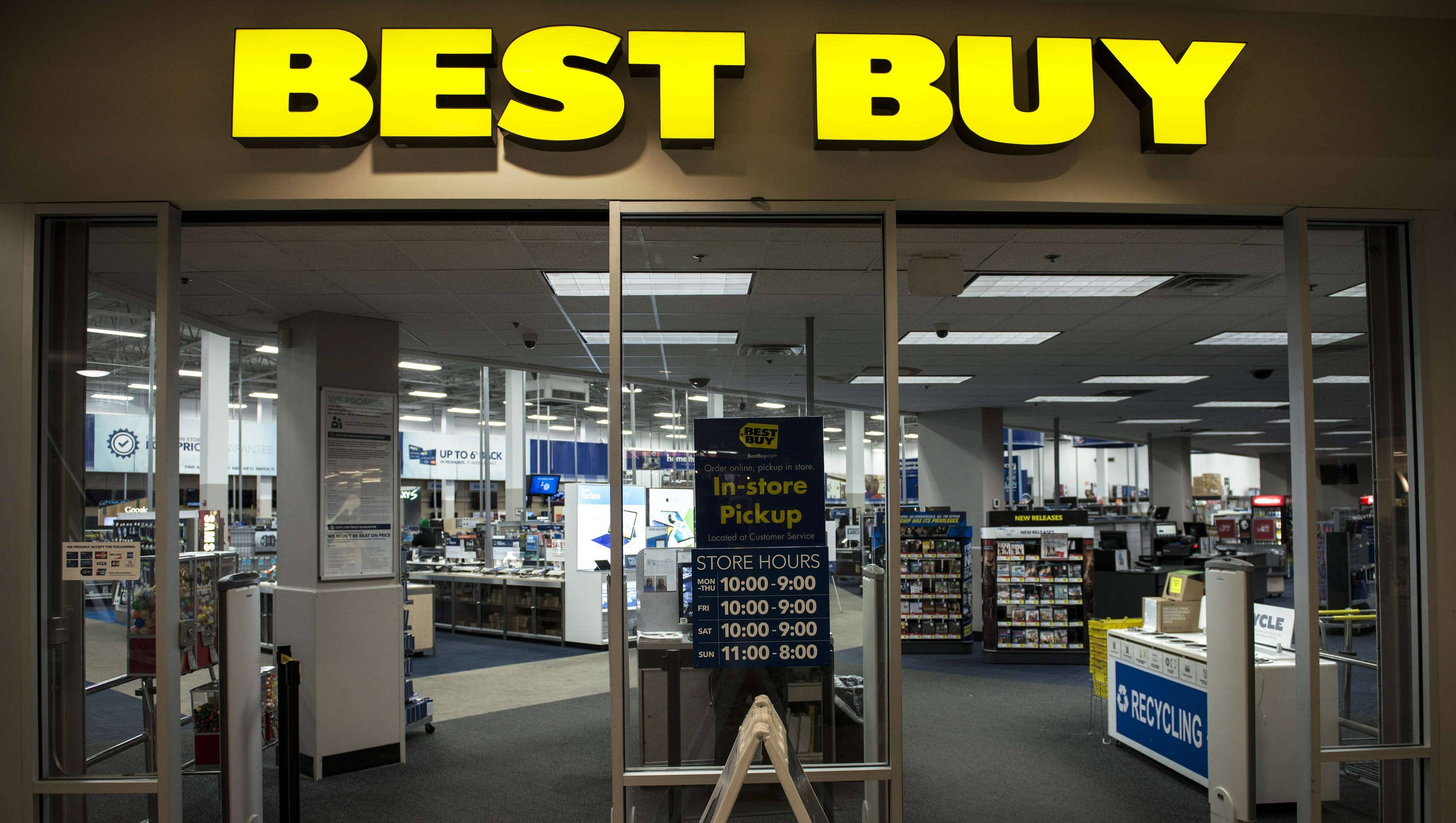 buy 桌布 壁紙 — 光線充足的Best Buy商店入口，玻璃門和黃色標誌揭示內部的電子產品通道。
