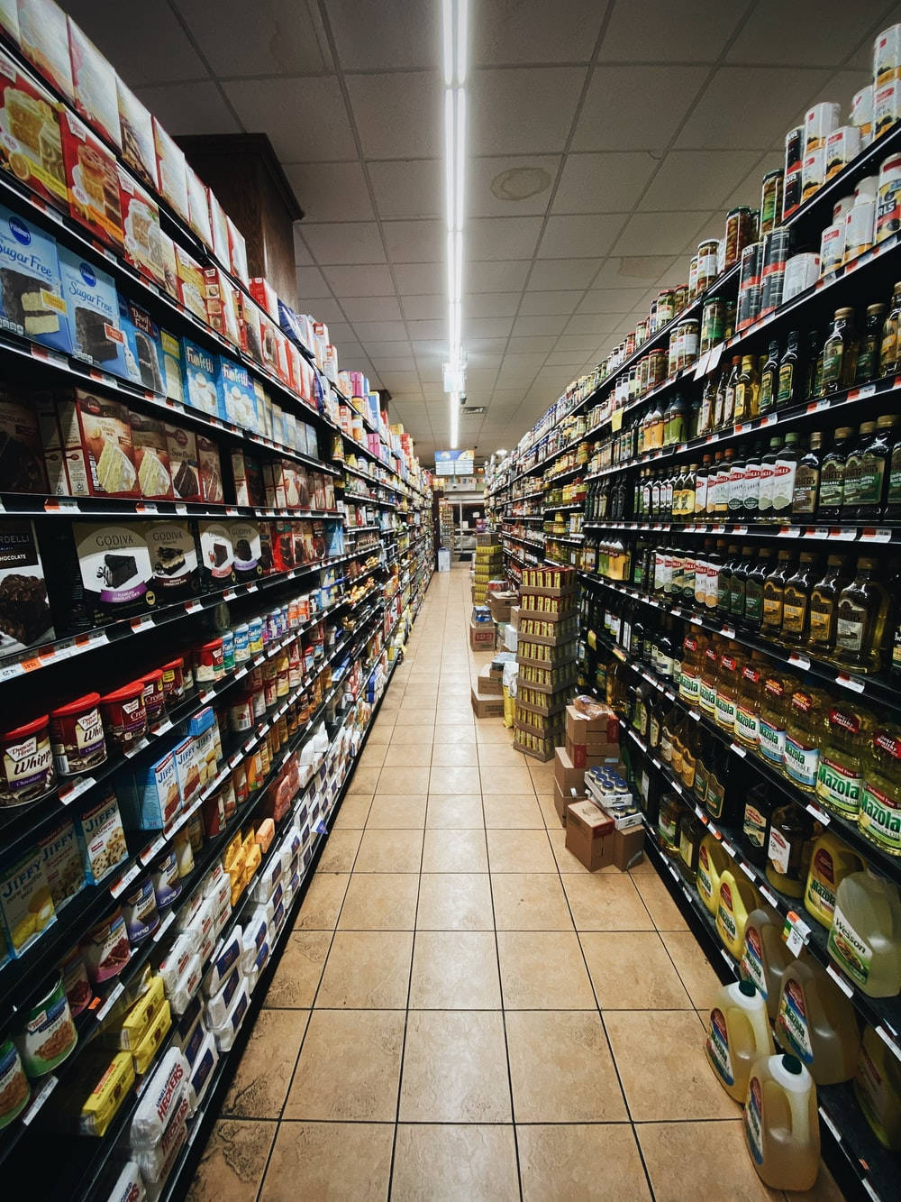 Shopping 桌布 壁紙 — 光線充足的雜貨店內一條長長的通道，貨架上擺滿了零食和食用油。