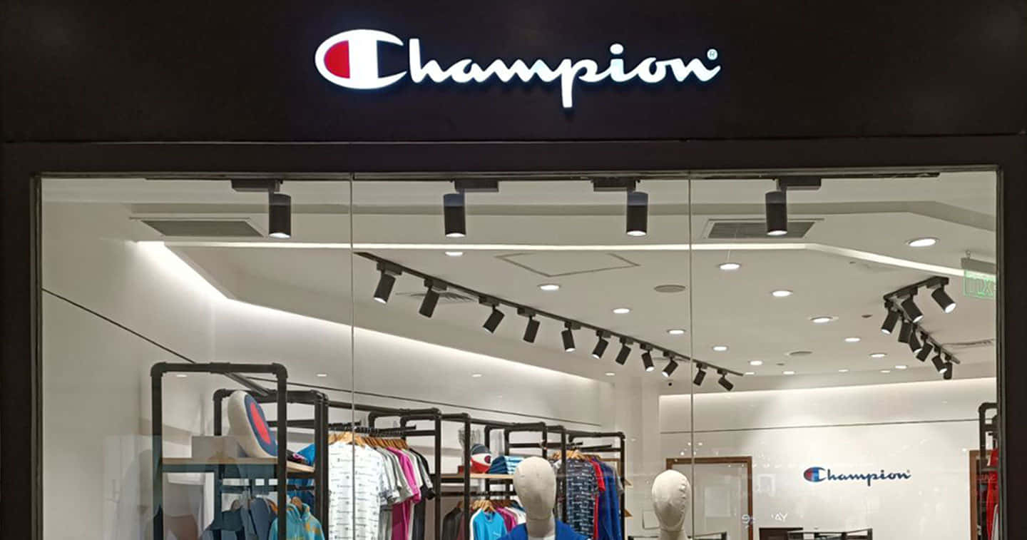 Champion 桌布 壁紙 — 光線明亮的Champion運動服飾店正面，透過玻璃門可看到人體模型和色彩繽紛的衣物架。
