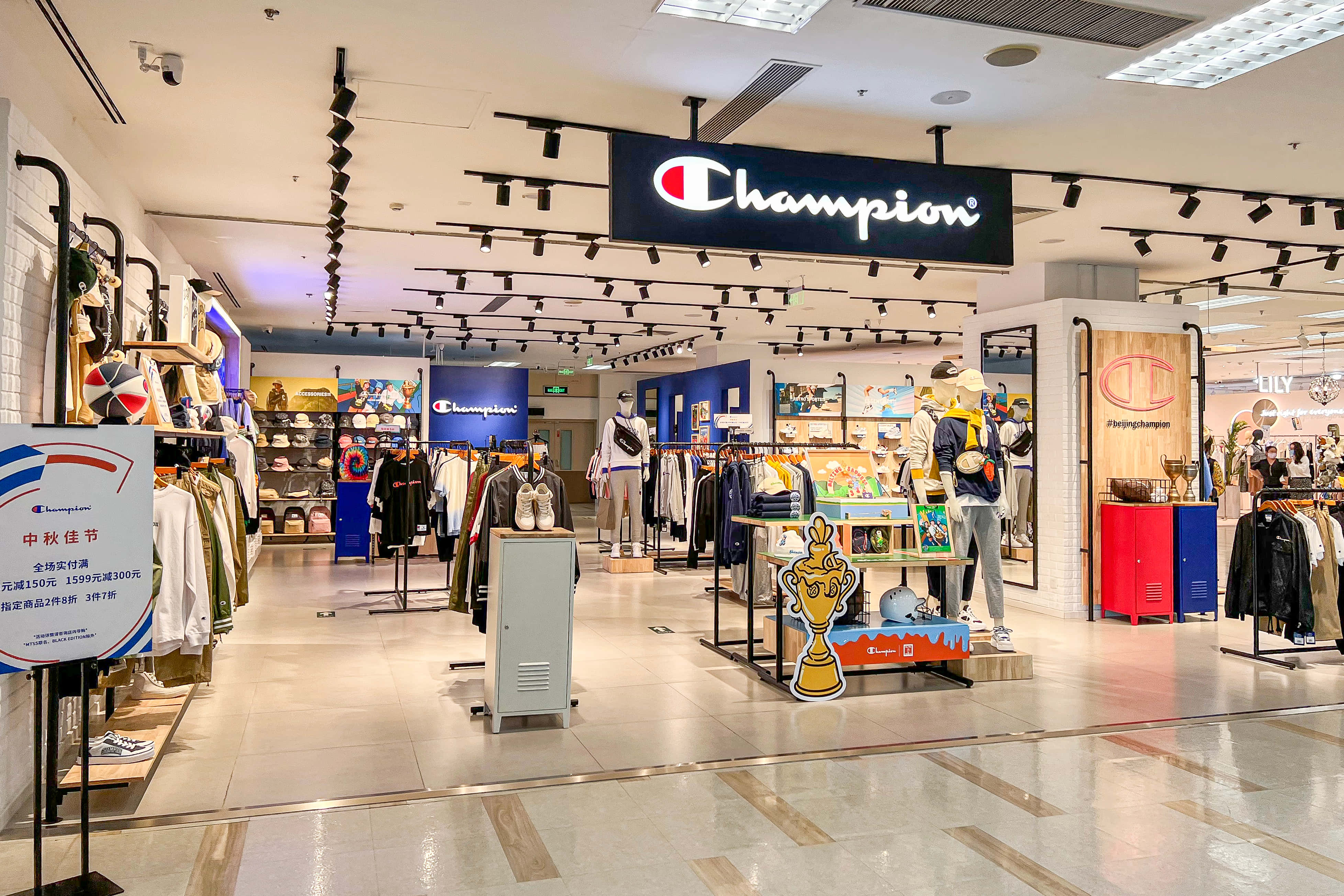 Champion 桌布 壁紙 — 光線明亮的Champion運動服飾店，展示人體模型、貨架和促銷展示，配以現代天花板燈光。