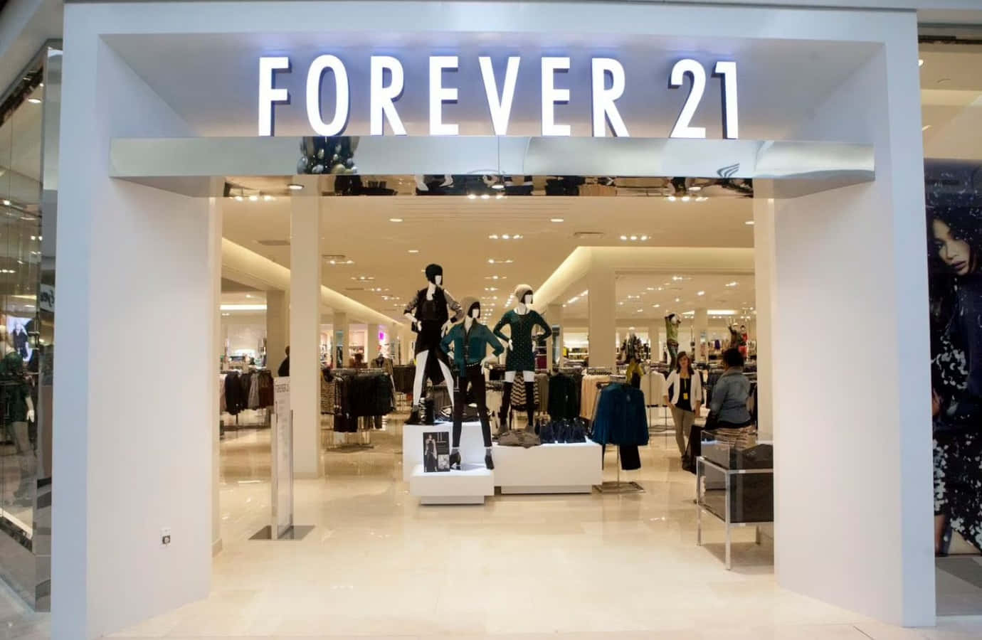 永遠21 桌布 壁紙 — 光線明亮的Forever 21商店入口，模特兒穿著時尚服裝在發光招牌下展示。