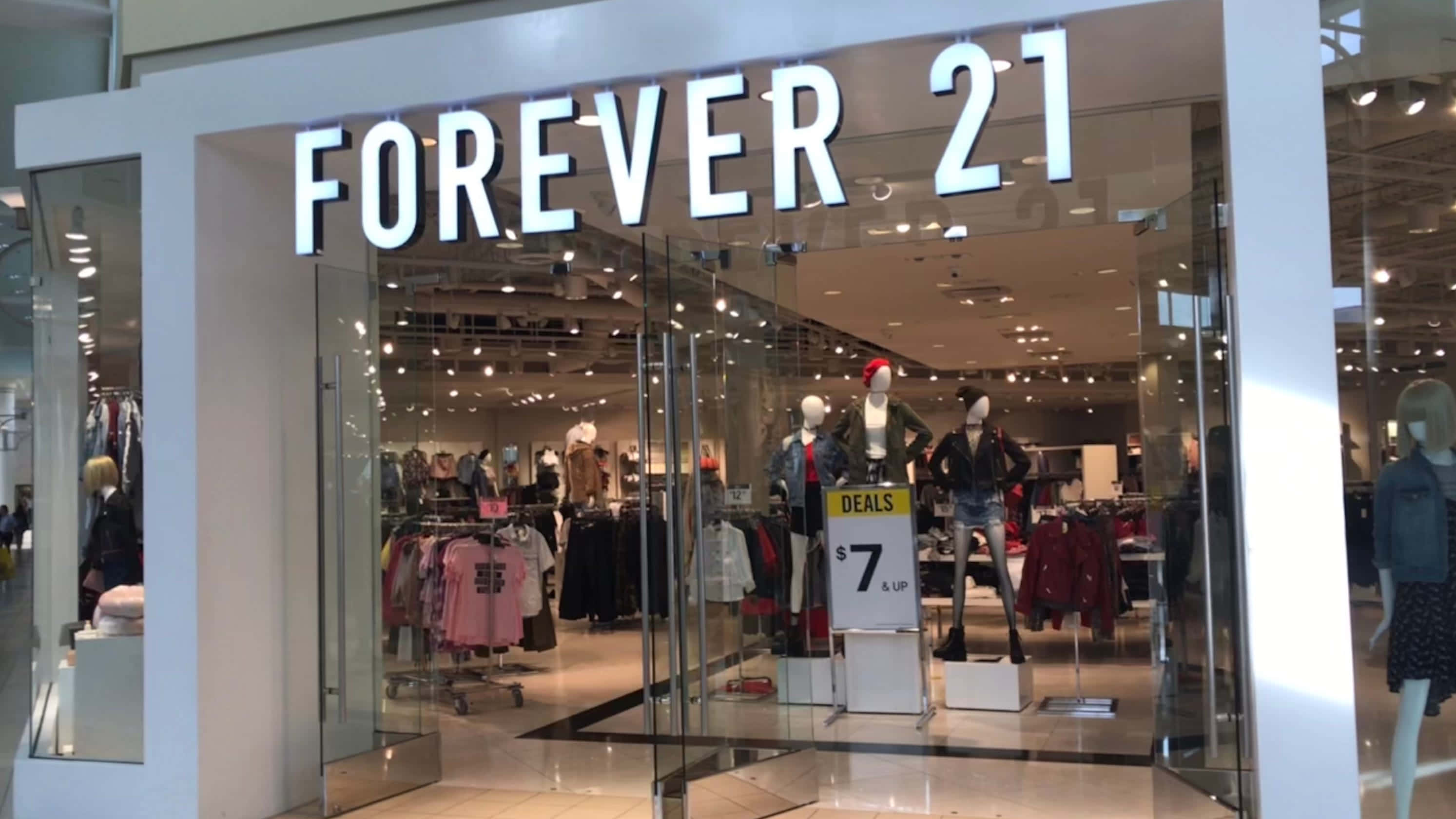 永遠21 桌布 壁紙 — 光線明亮的Forever 21店鋪正面，設有玻璃門、人體模型和展示色彩繽紛衣物的貨架。