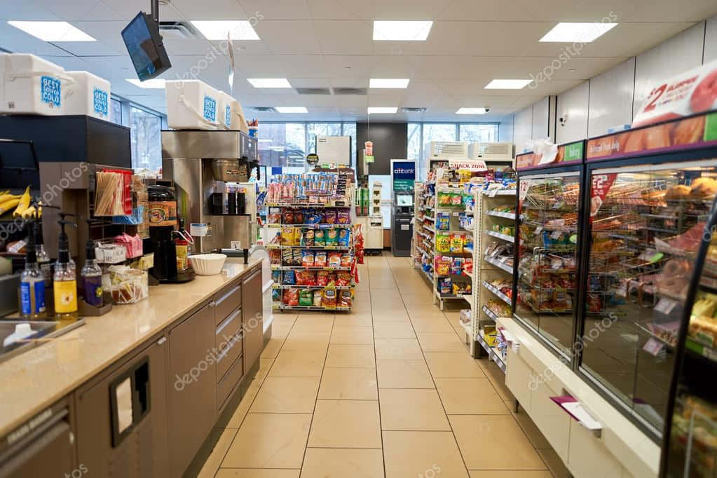 7-ELEVEN 桌布 壁紙 — 光線明亮的便利商店通道，設有冷藏櫃、零食和咖啡站，在螢光燈下。