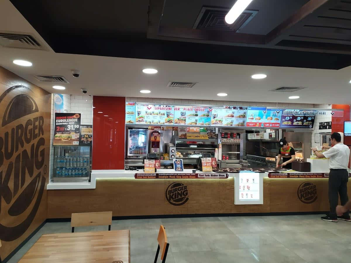 漢堡王 桌布 壁紙 — 光線明亮的漢堡王速食餐廳內部，有顧客在櫃檯點餐，員工在服務窗口後工作。