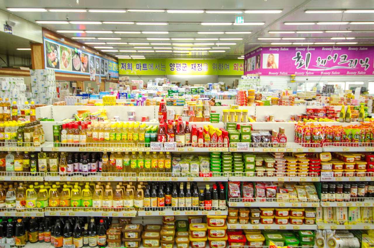Shopping 桌布 壁紙 — 光線明亮的超市走道，擺滿了色彩繽紛的醬料和調味品瓶罐。