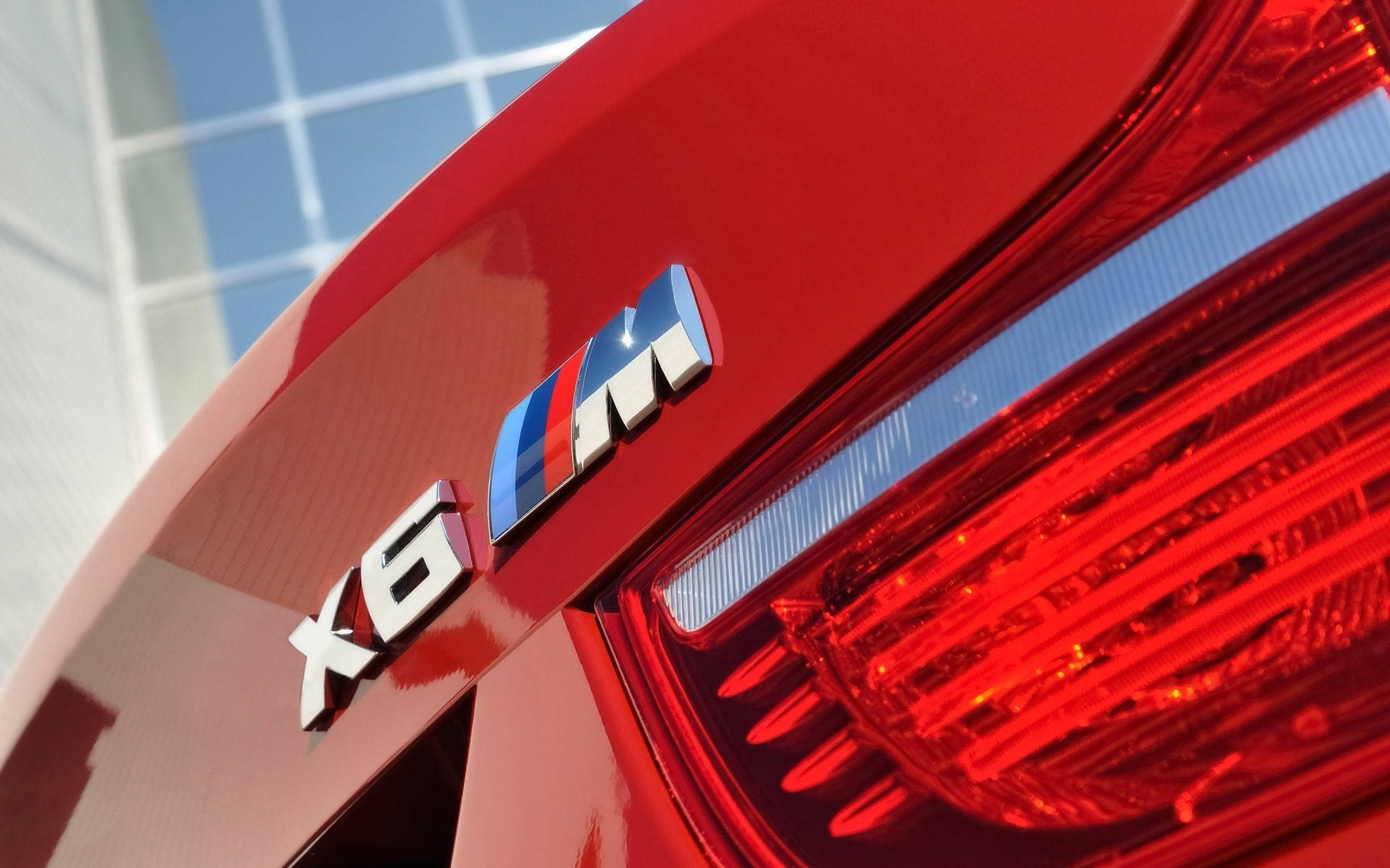m 桌布 壁紙 — 光面紅色BMW X6 M徽章及尾燈反射明亮藍天的特寫。